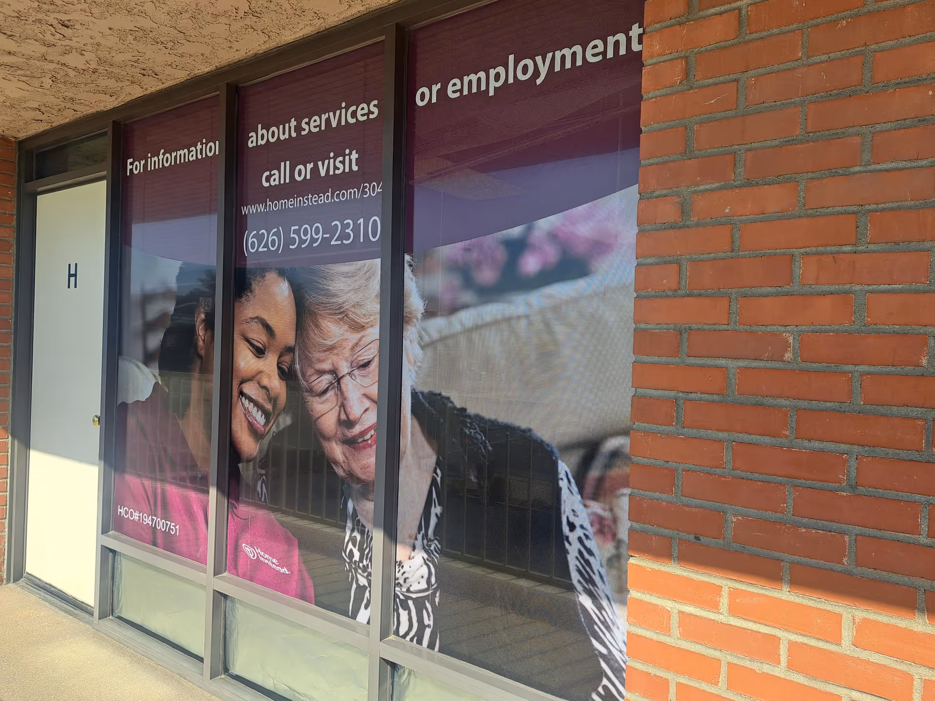 Storefront windows display Home Instead promotional graphics of smiling caregivers and seniors.