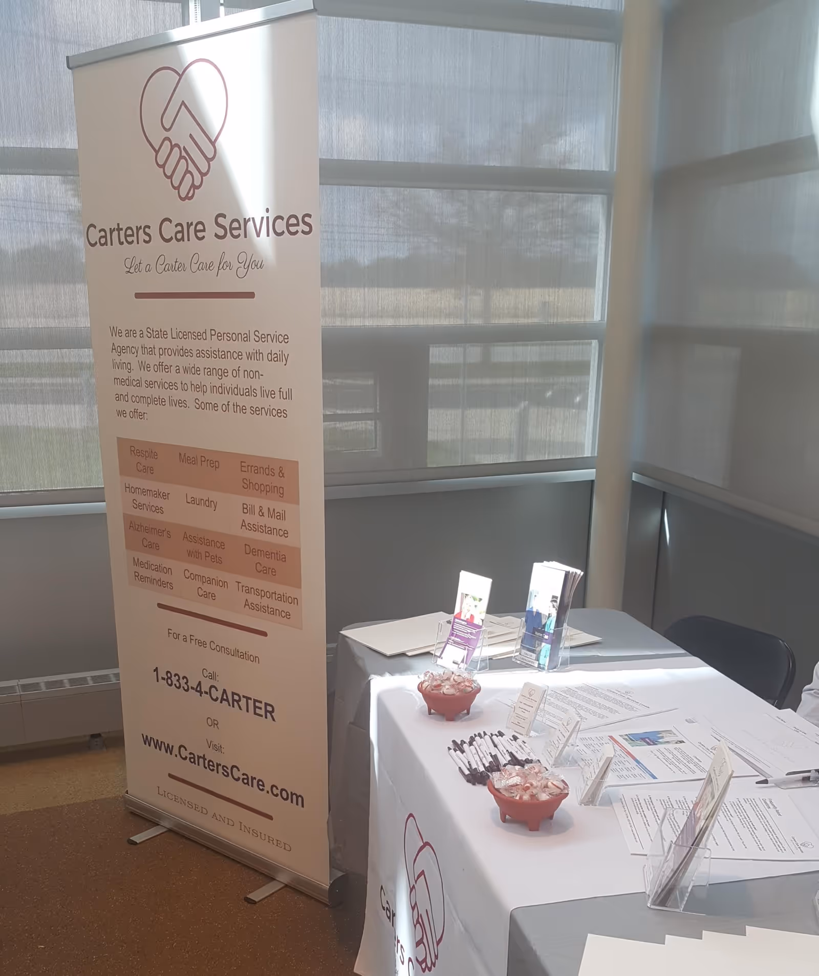 A tall Carters Care Services banner stands beside a brochure table indoors.