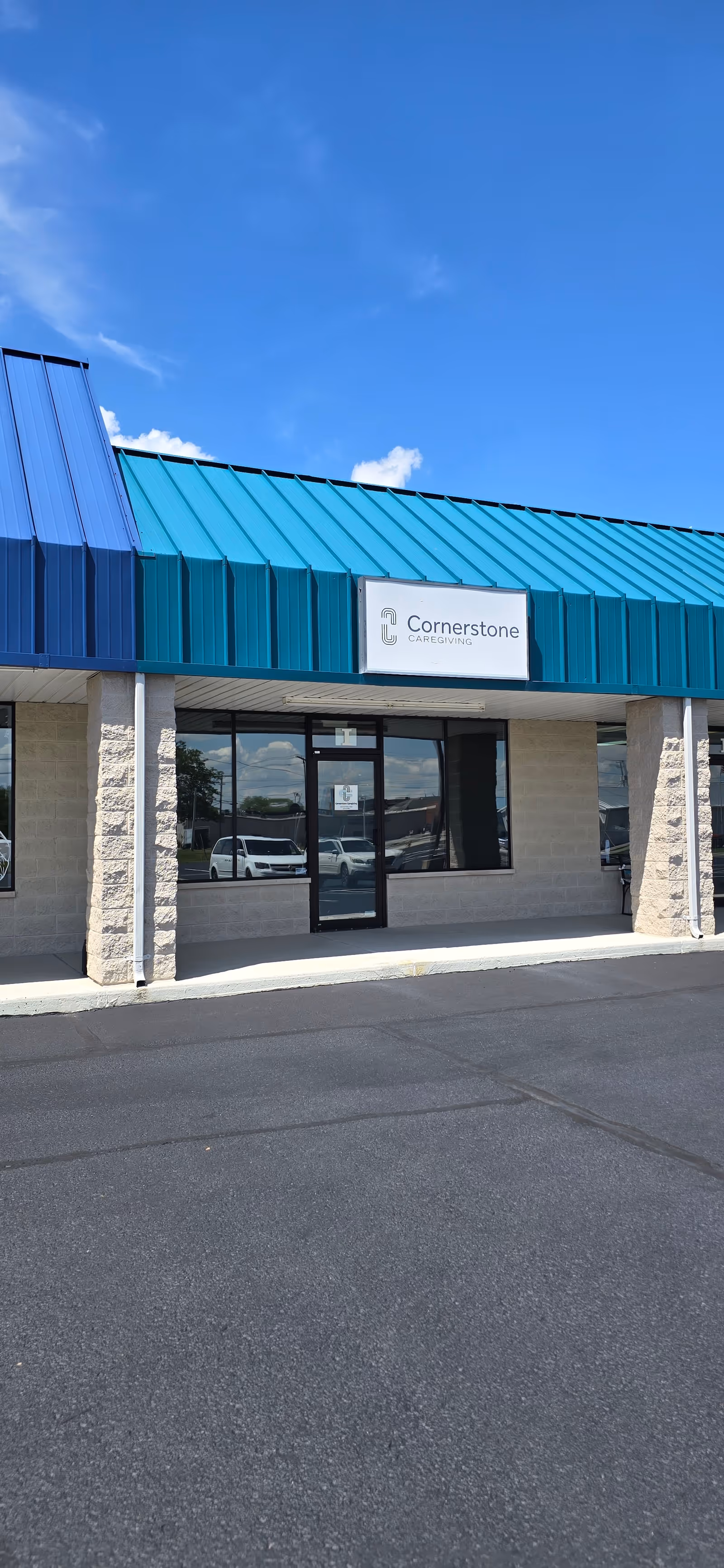 Exterior view of Cornerstone Caregiving with a blue roof, glass entrance, and sign.