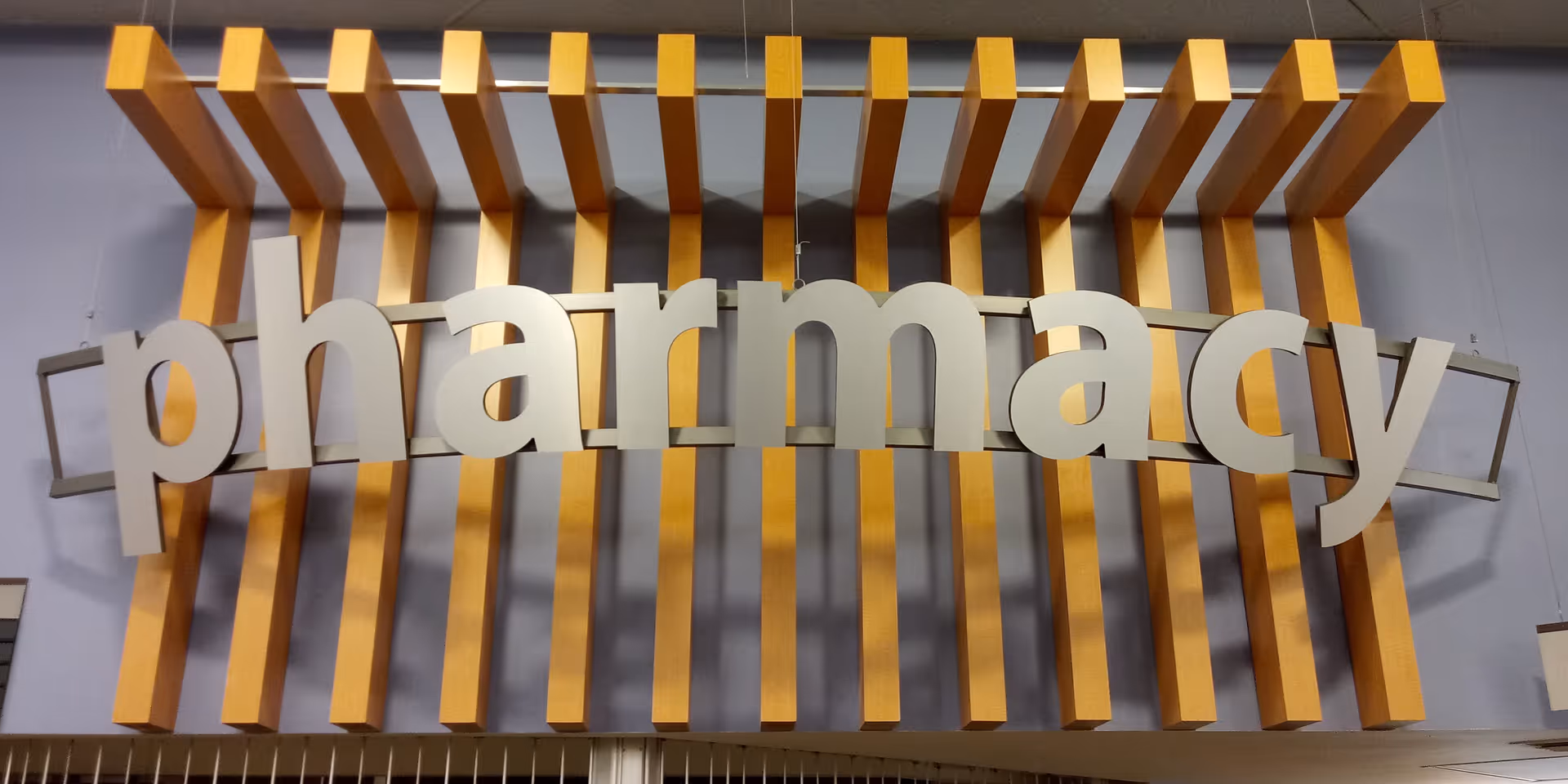 Large interior sign reading 'pharmacy' with orange vertical slats behind it.