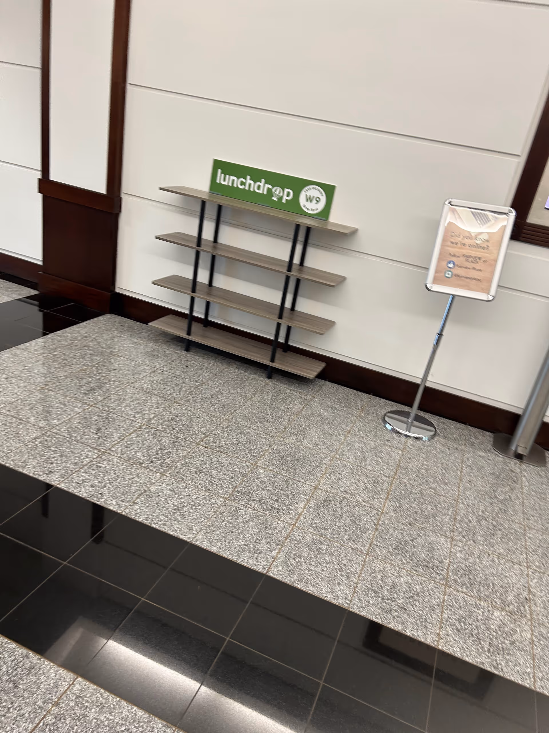 Indoor lobby area features a four-shelf rack and a sign on a stand.