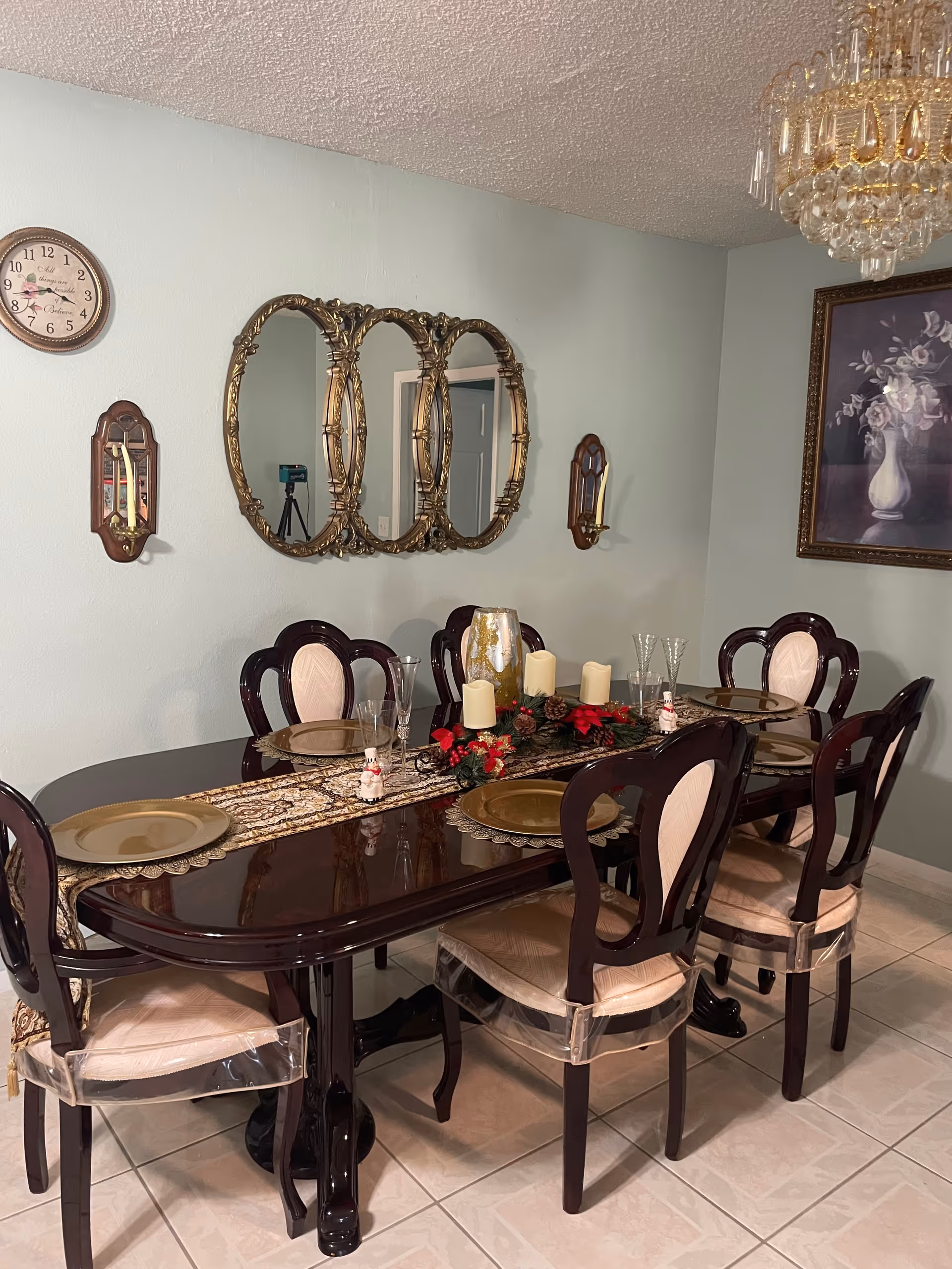 Elegant dining room with a long dark table, ornate chairs, and chandelier lighting.