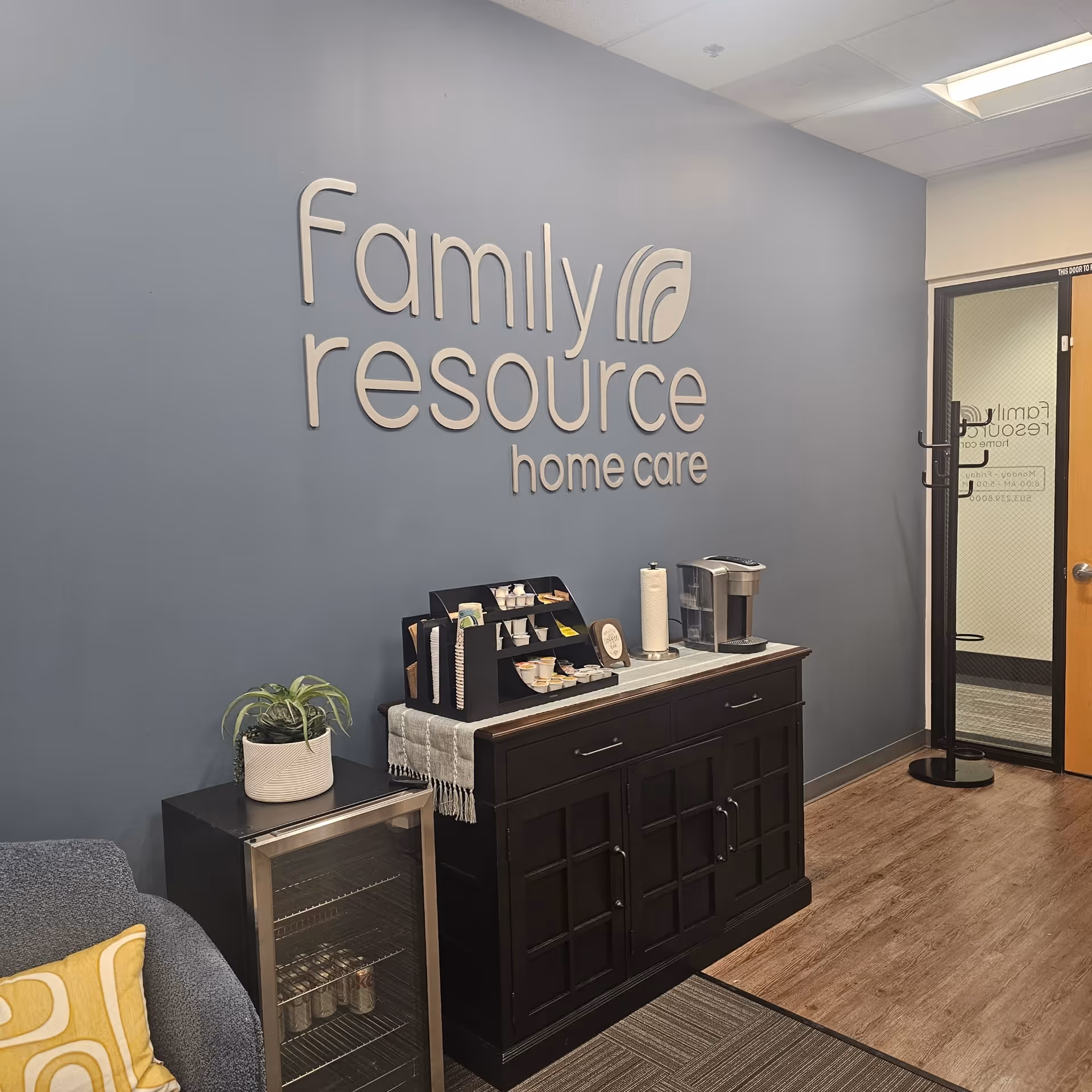 Blue-walled reception area with 'Family Resource Home Care' sign and coffee station.