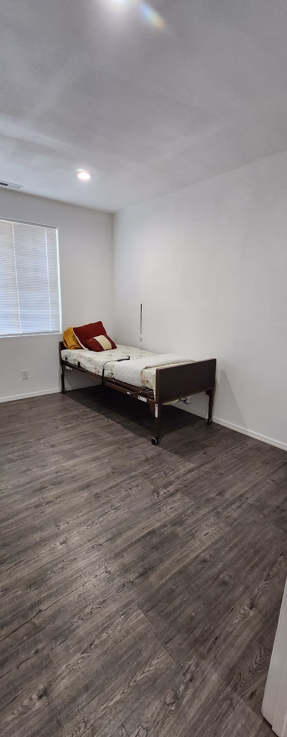 Empty bedroom with a single adjustable bed near a window with blinds.