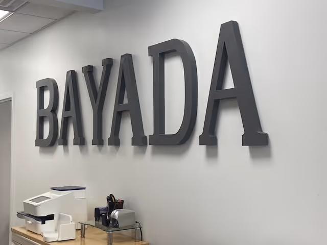 Interior wall with large BAYADA letters and office equipment on a counter.