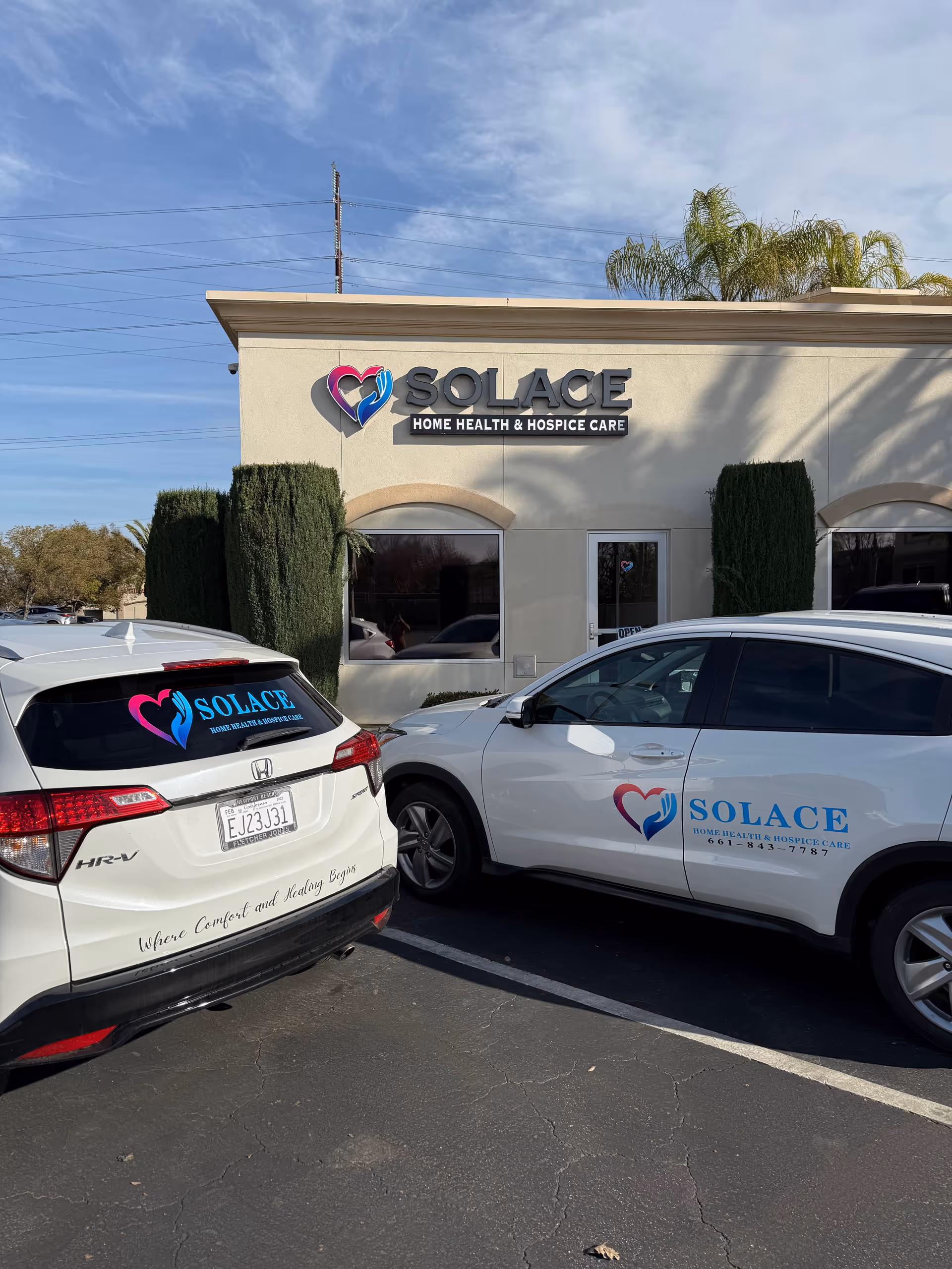 Exterior view of Solace healthcare building with two branded vehicles parked in front and palm trees.