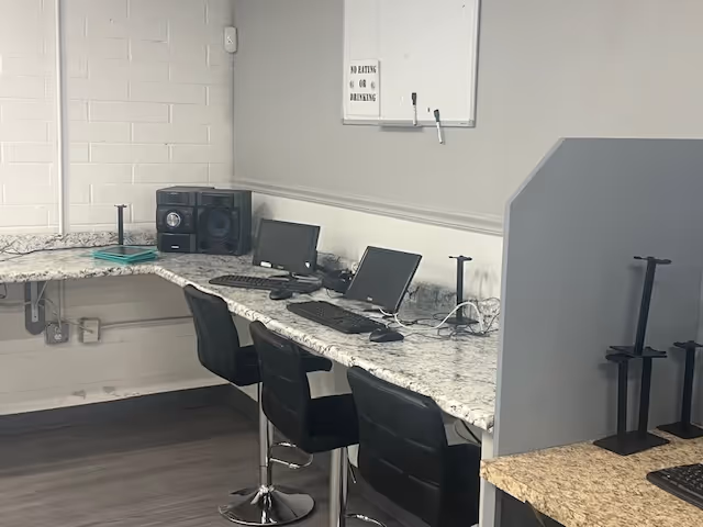 Row of computer stations along a marble counter in a small office area.