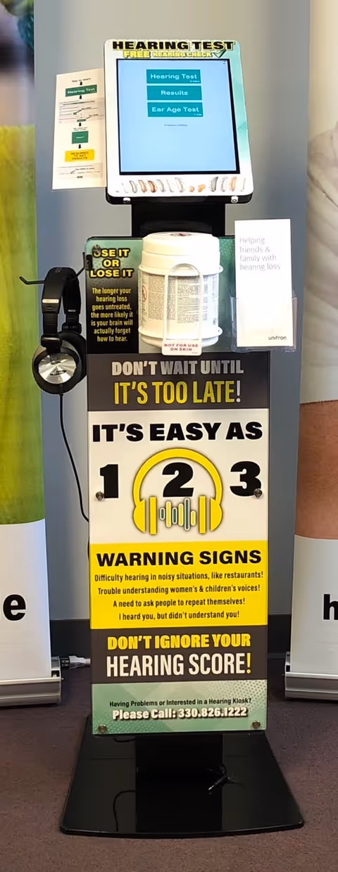 Hearing test kiosk with headphones and signs inside a senior living facility.