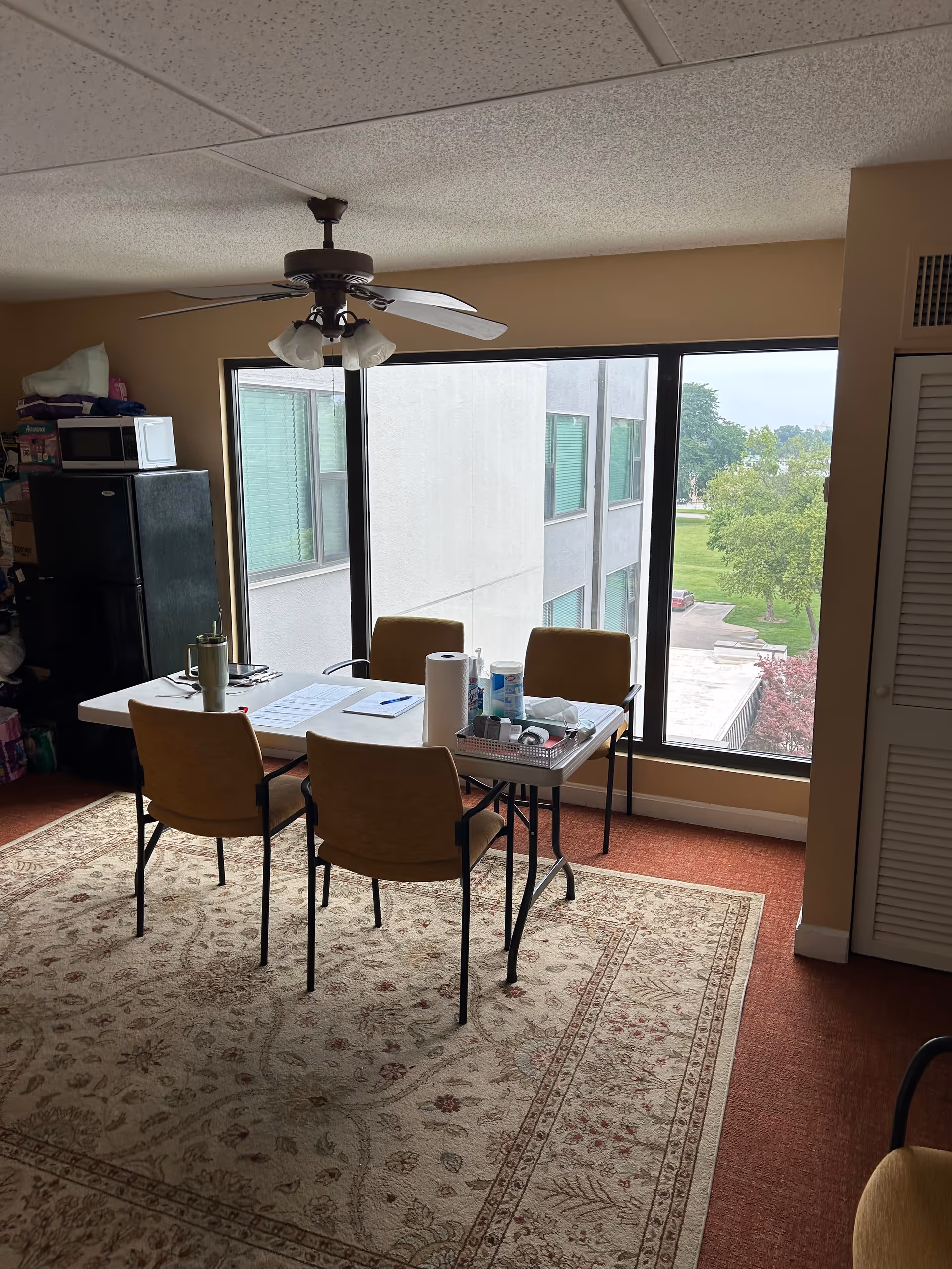 Indoor dining area with a four-chair table, large window, and supplies on the table.