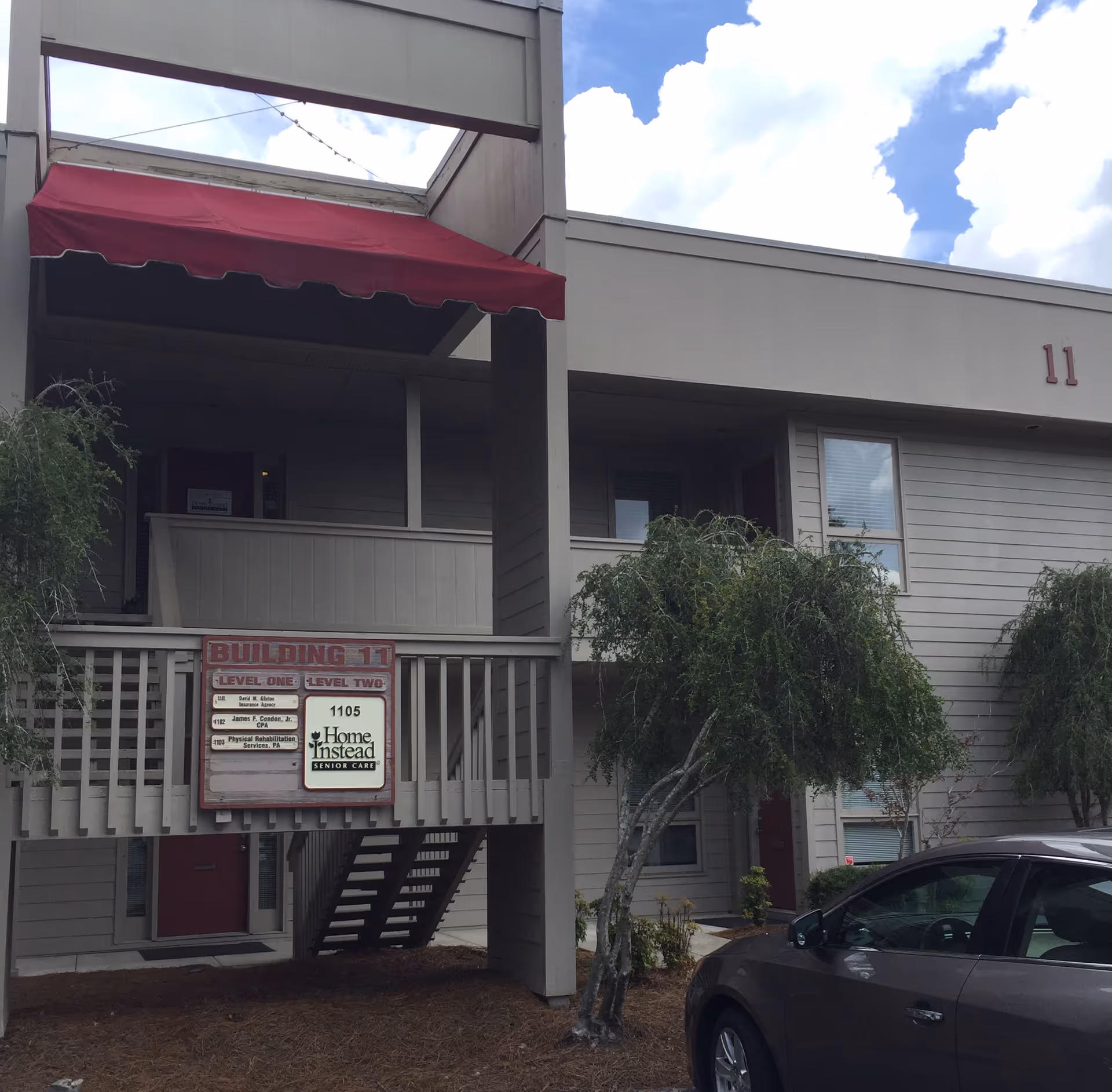 Two-story building exterior with a red awning and Home Instead sign.