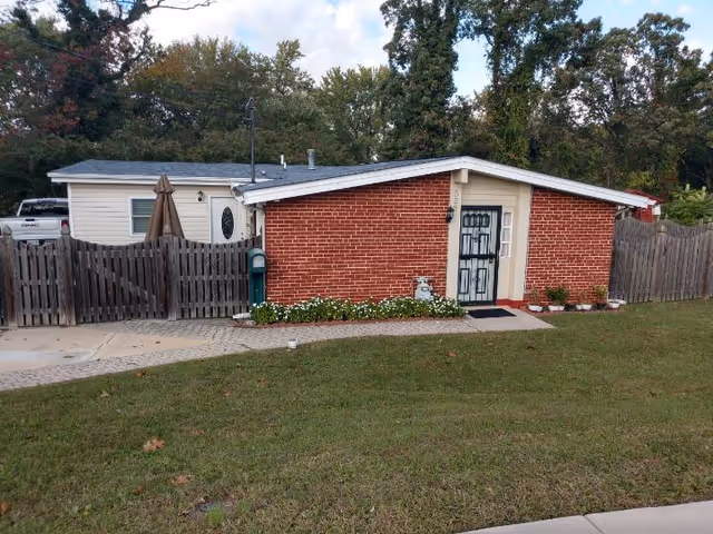 Front exterior of a single-story brick facility with a gate, fence, and lawn.