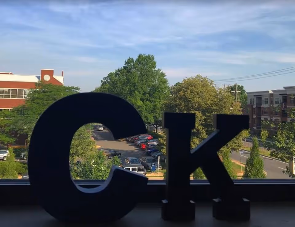 Indoor windowsill with large CK letters overlooking street and trees.