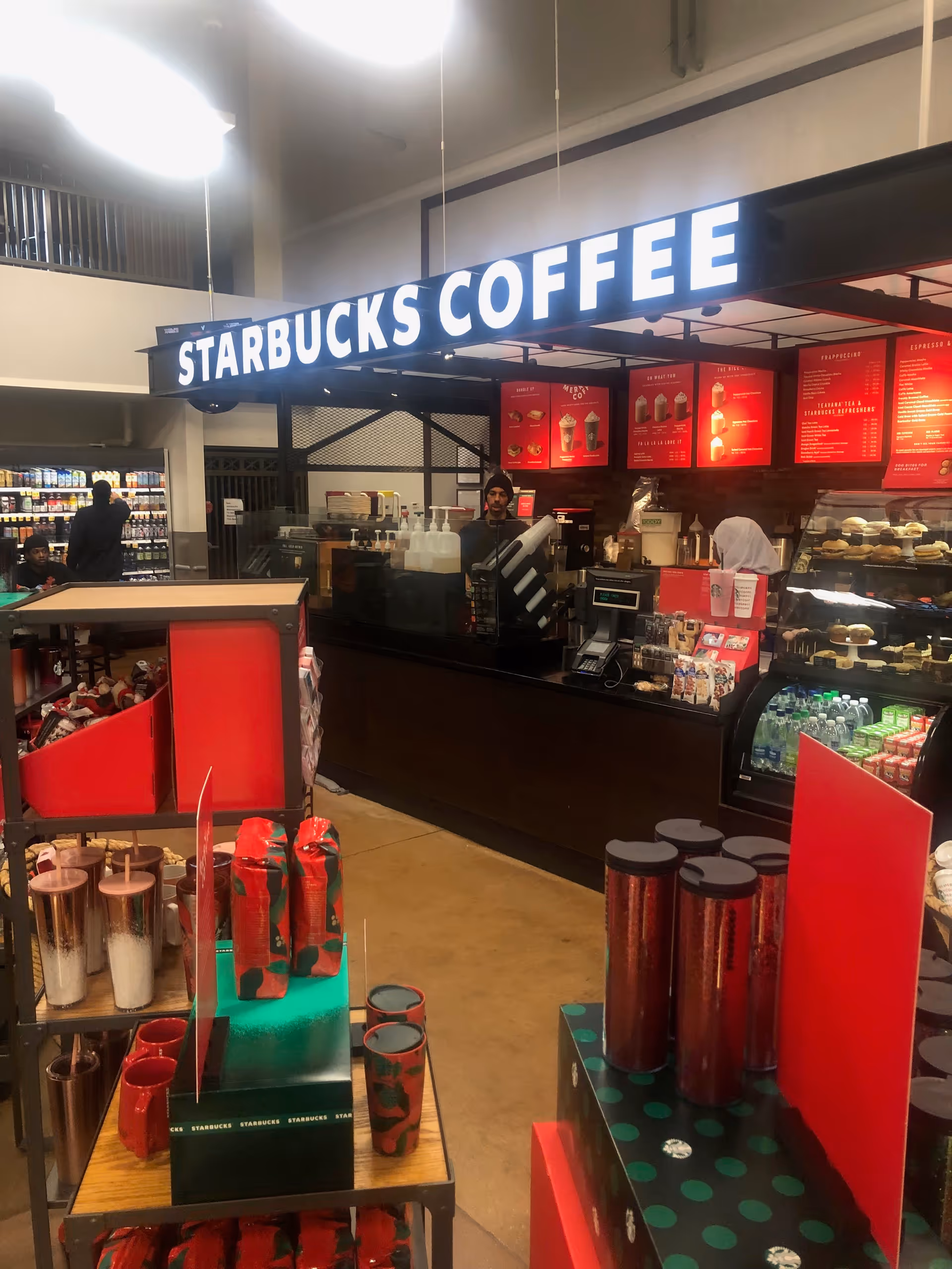 Starbucks counter inside a store with menu boards and pastry displays.
