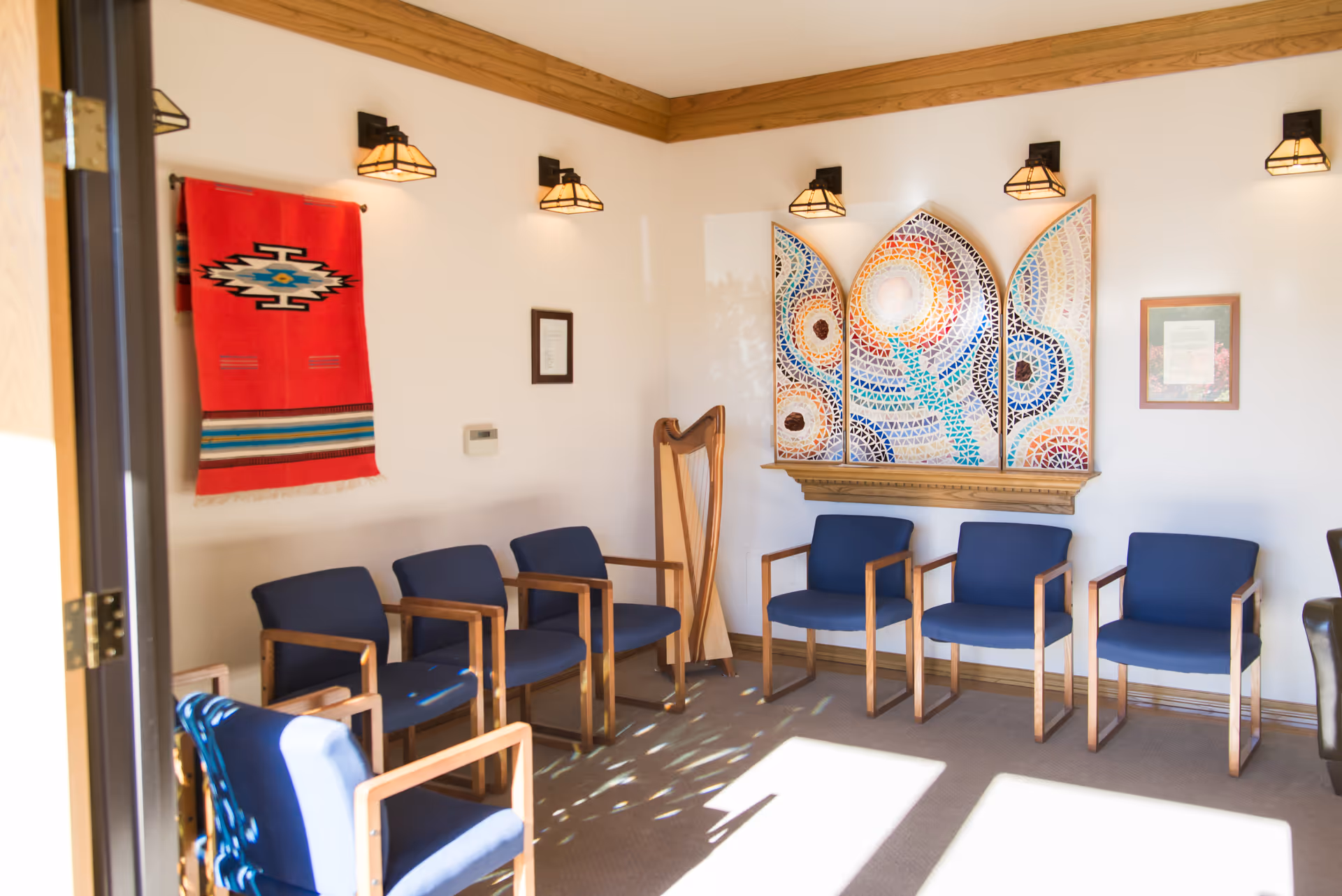 Bright interior waiting area in a senior living facility with blue chairs and wall art.