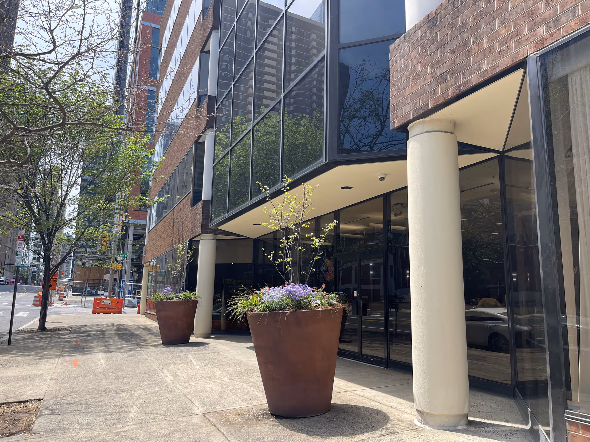 Exterior view of BAYADA Assistive Care building entrance with glass walls, brick facade, and large planters.