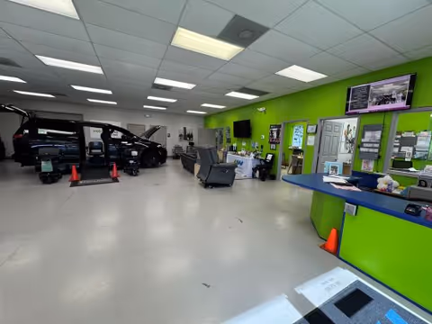 Interior MobilityWorks showroom and service area with a black van and lime-green reception desk.