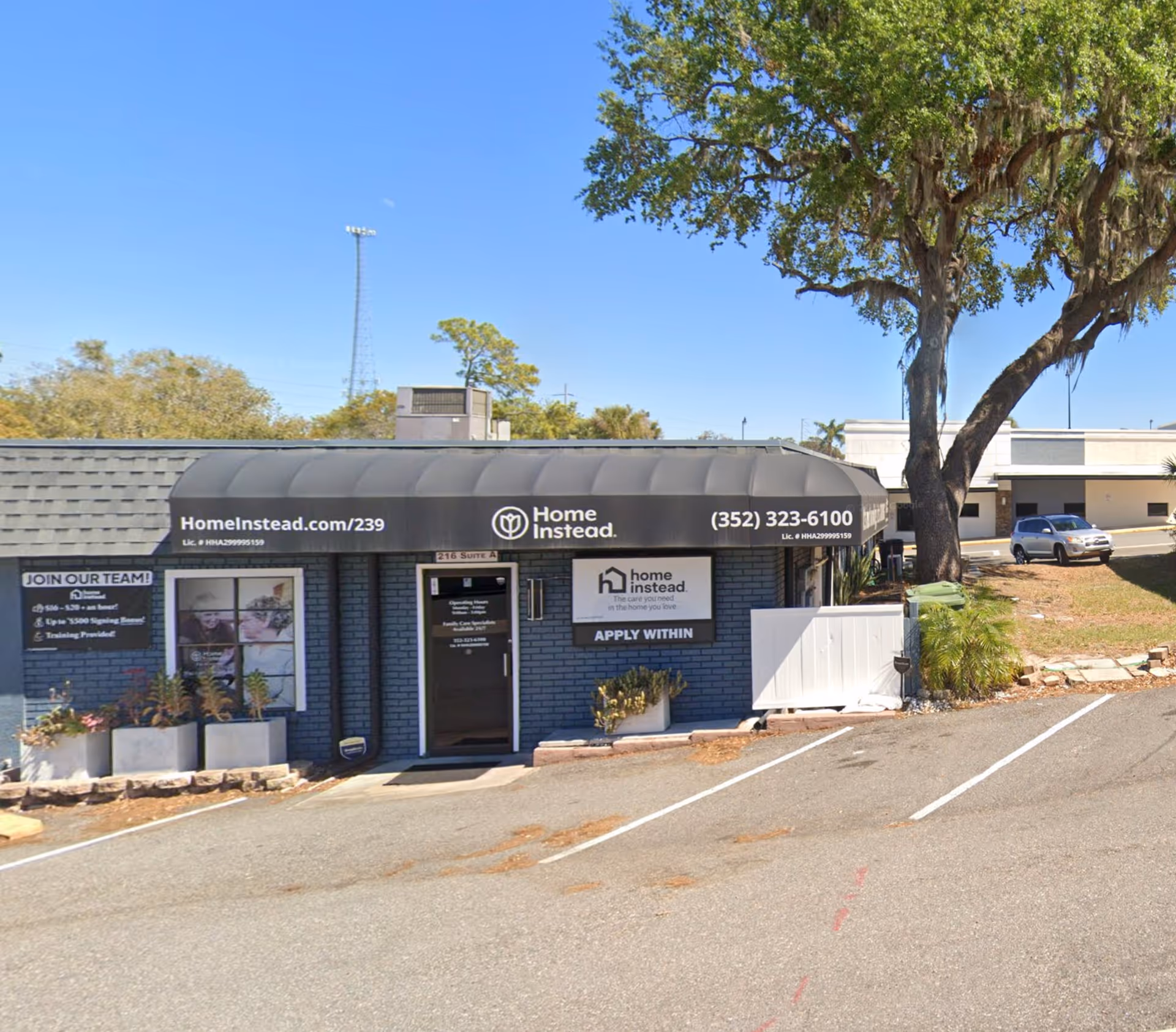 Front exterior of a Home Instead facility with black awning and parking area.