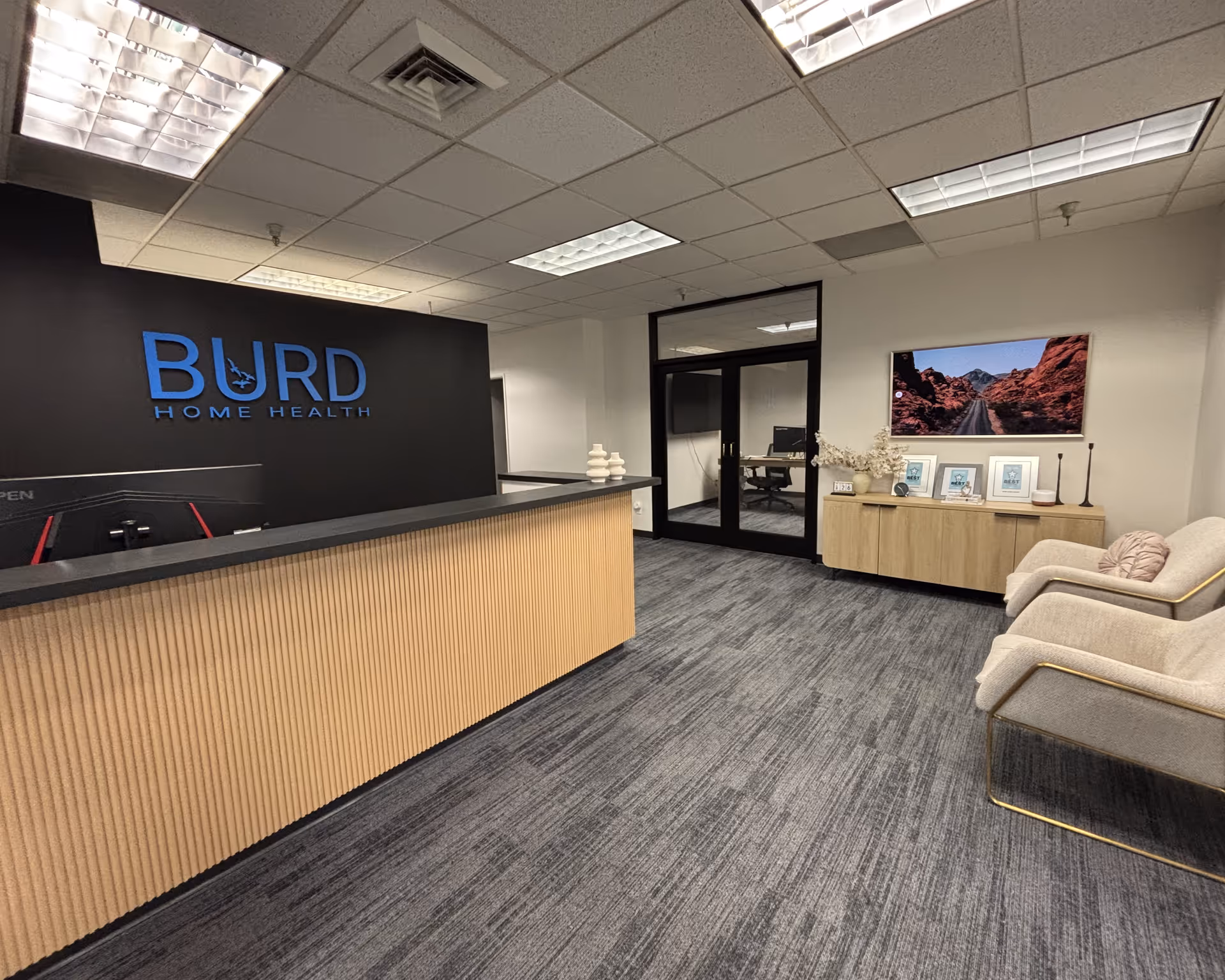 Reception area with Burd Home Health sign, wooden front desk, and seating.
