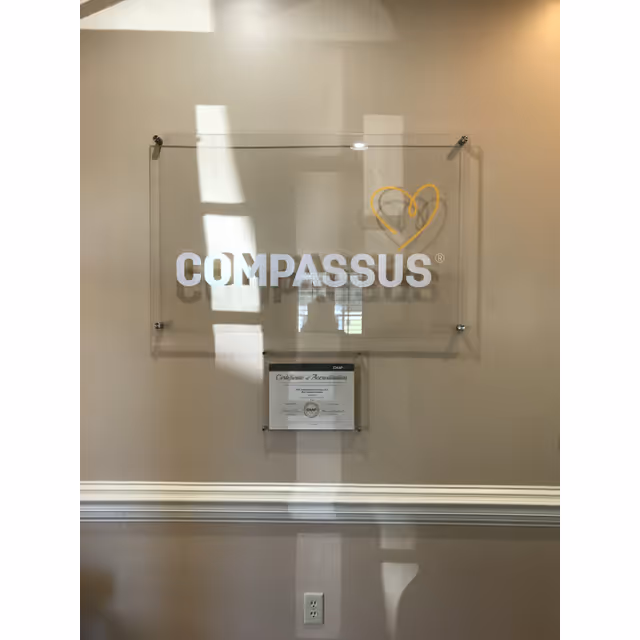 Interior wall with Compassus sign and framed certificate plaque beneath it.
