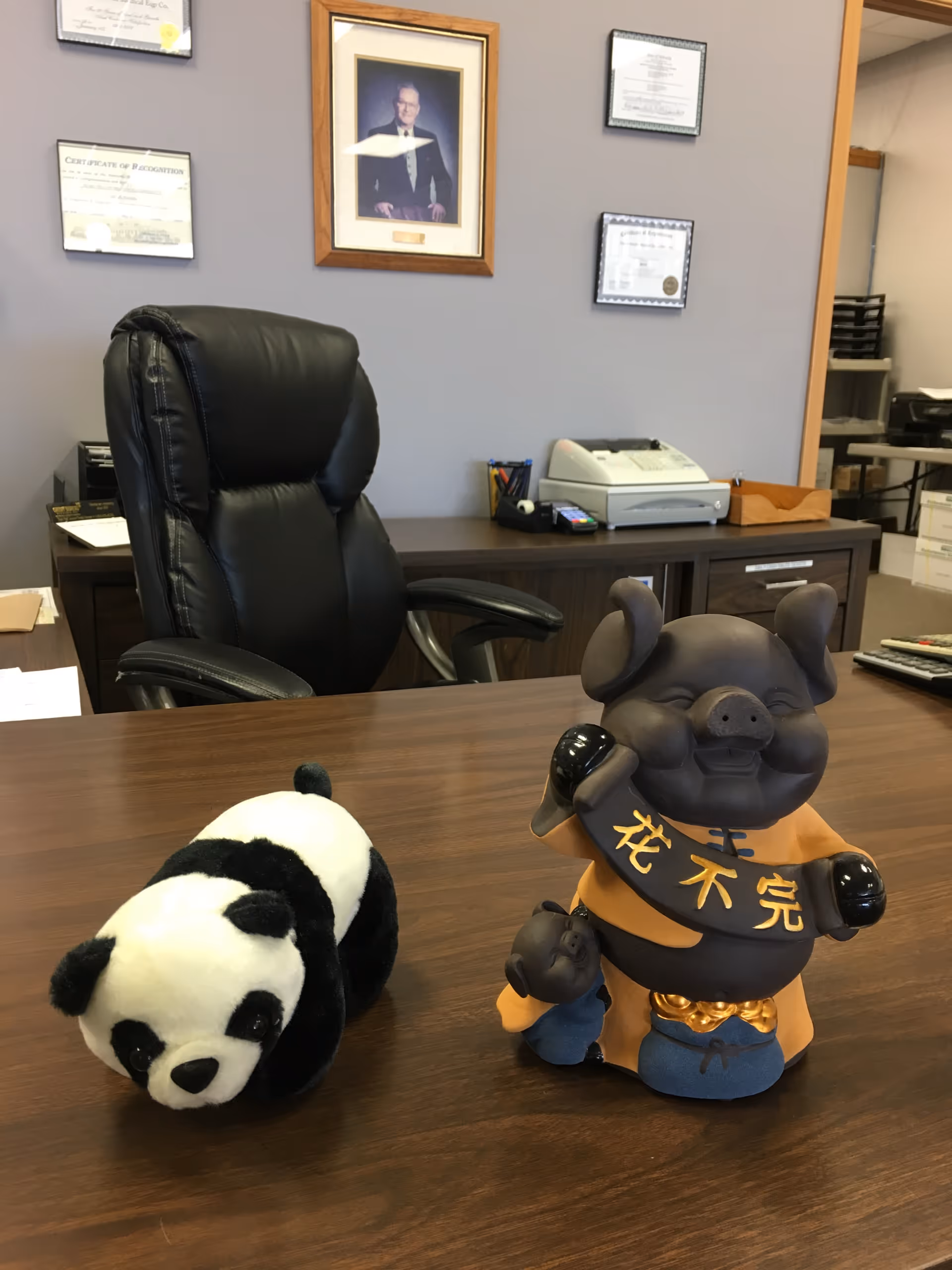 Office desk in a senior living facility with panda figurines and certificates on wall