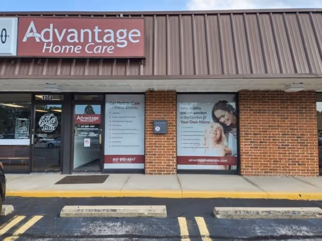 Exterior of Advantage Home Care storefront with brick facade and posters.