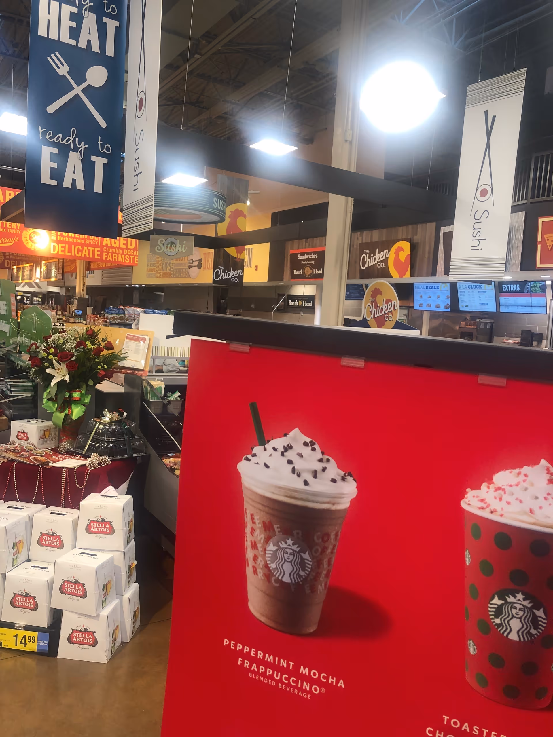 Inside a Kroger store, a large beverage advertisement dominates the foreground near checkout area.