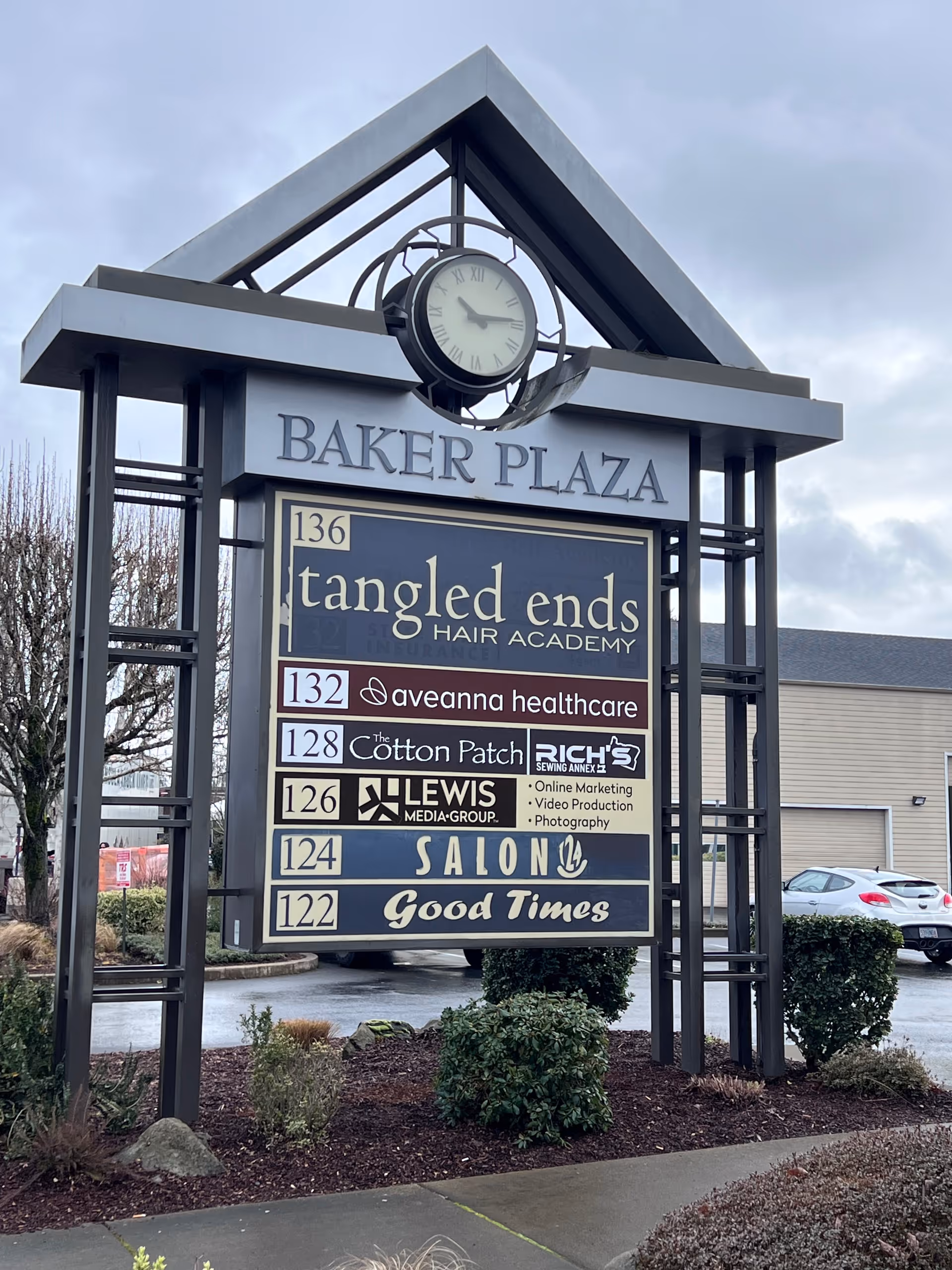 Outdoor sign structure reading Baker Plaza with tenants like Aveanna Healthcare and a clock.