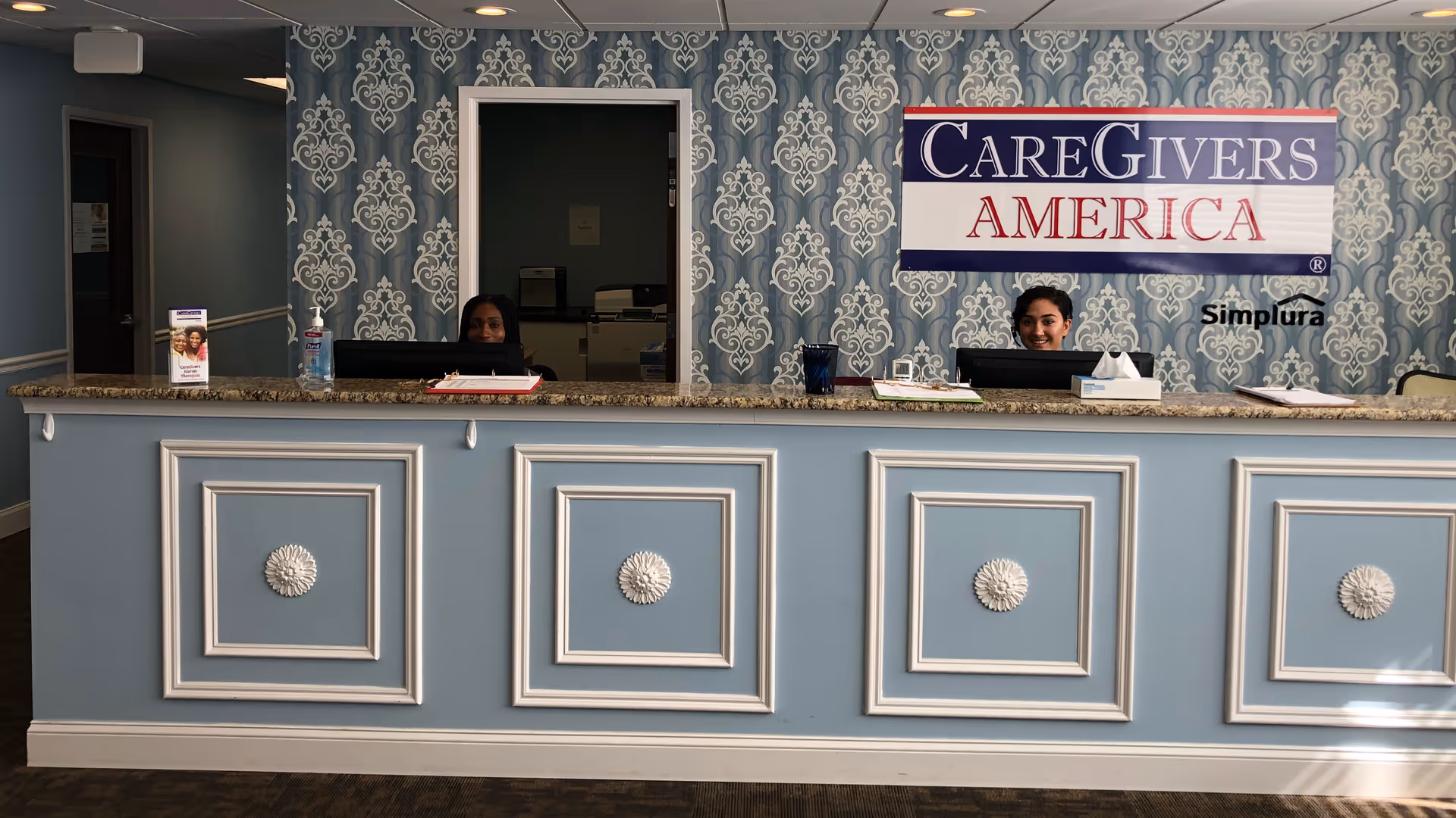 Reception desk in a CareGivers America facility with two staff behind counter