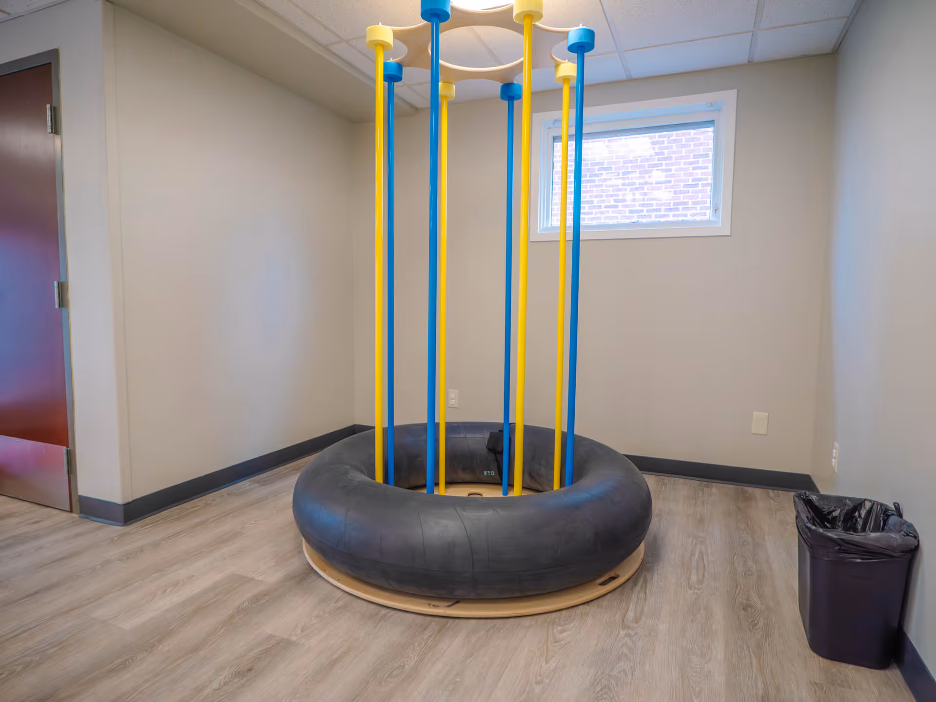 Therapy room with circular inflatable surface and tall yellow and blue poles.