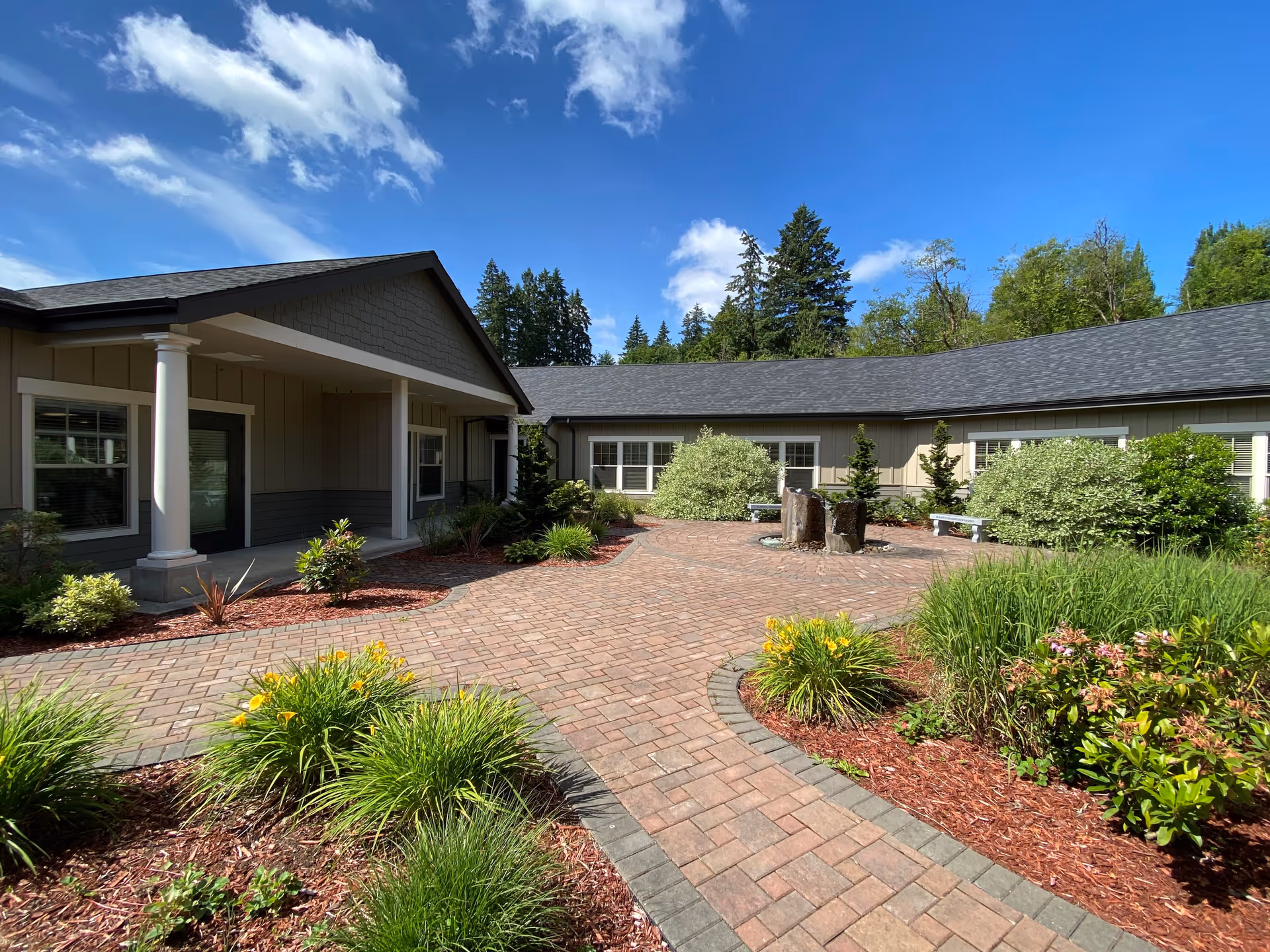 Exterior courtyard of a senior living facility with brick path and shrubbery
