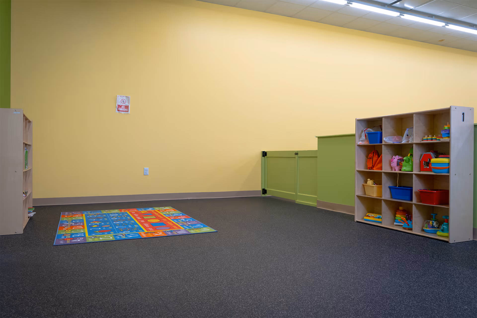 Bright yellow playroom with toy shelves, a colorful mat, and organized storage.