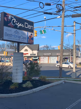 Outdoor street scene featuring a large sign for Best Home Care Inc beside The Cigar Den.