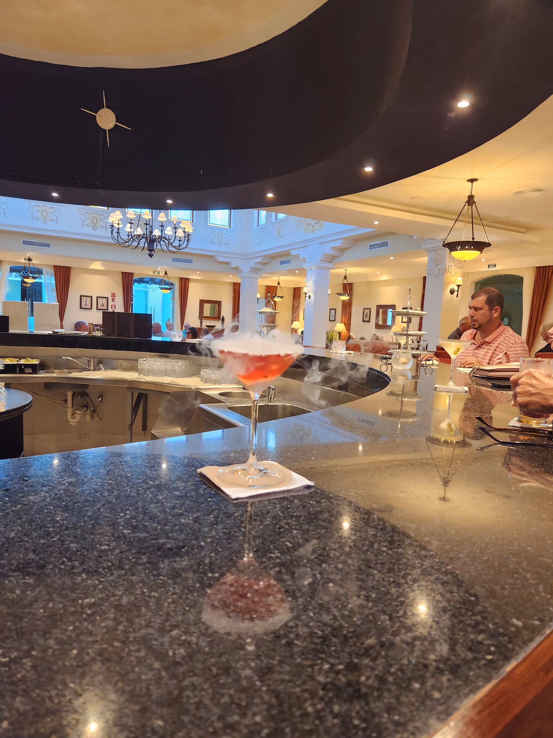 Smoky cocktail on a granite bar counter in a bright lounge interior.