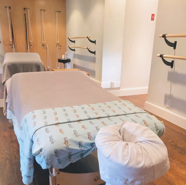 Treatment room in a senior living facility with massage table and wall-mounted bars.