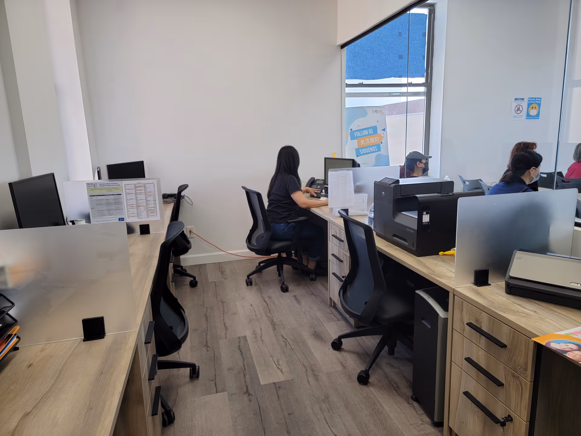 Interior office area at Royal Care with desks, chairs, computers, and printers.