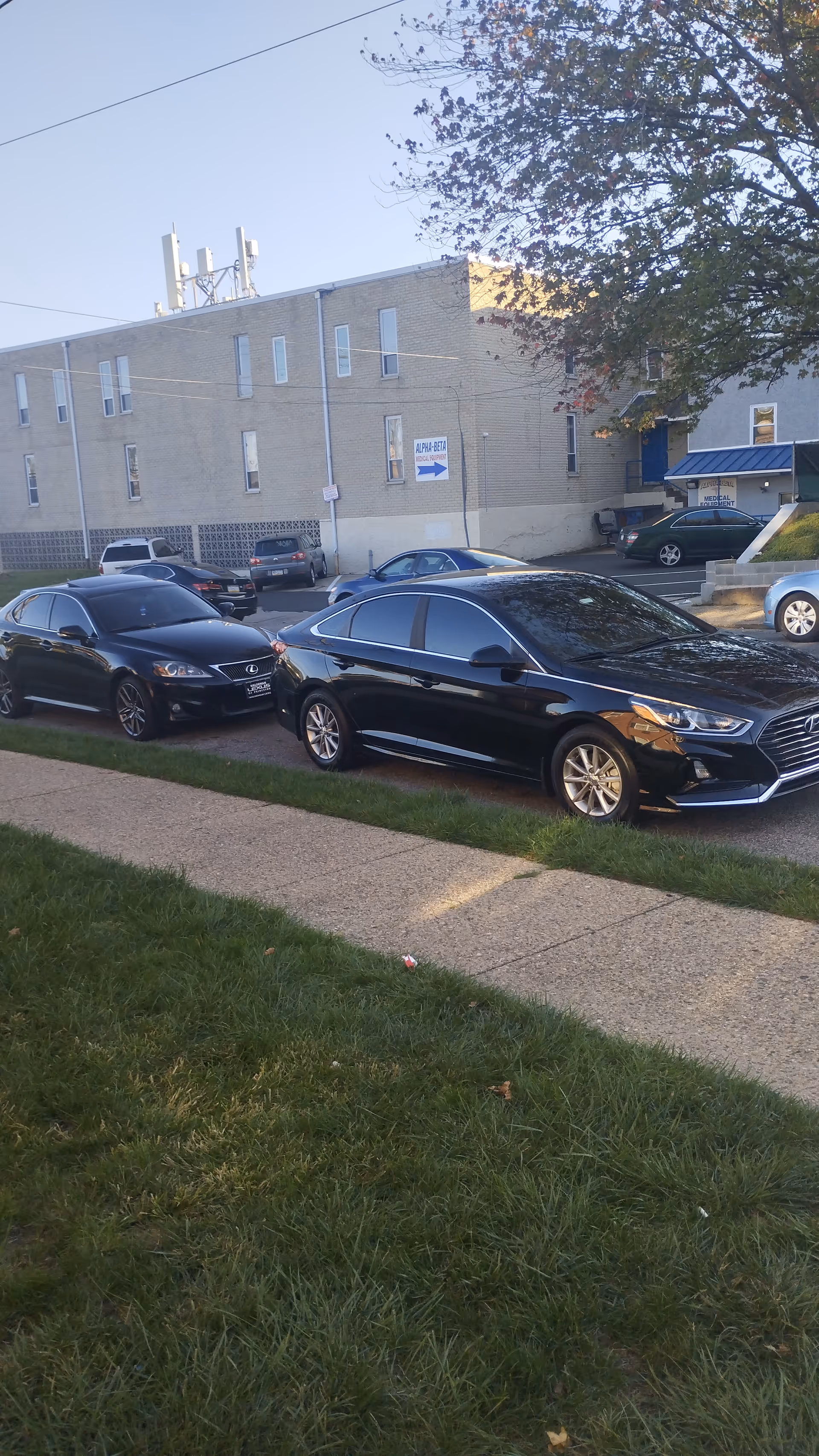 Exterior view of a senior care building with parked cars along a sidewalk.
