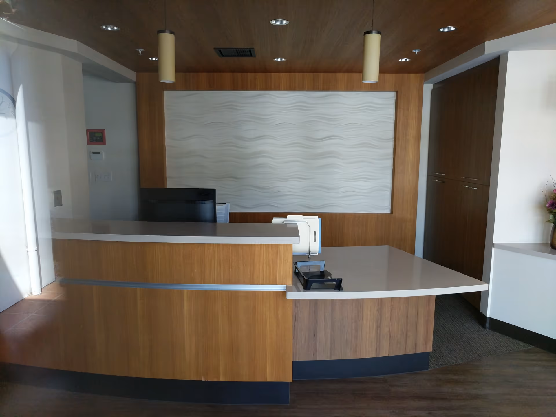 Modern reception desk in a wood-paneled interior lobby with a textured wall.