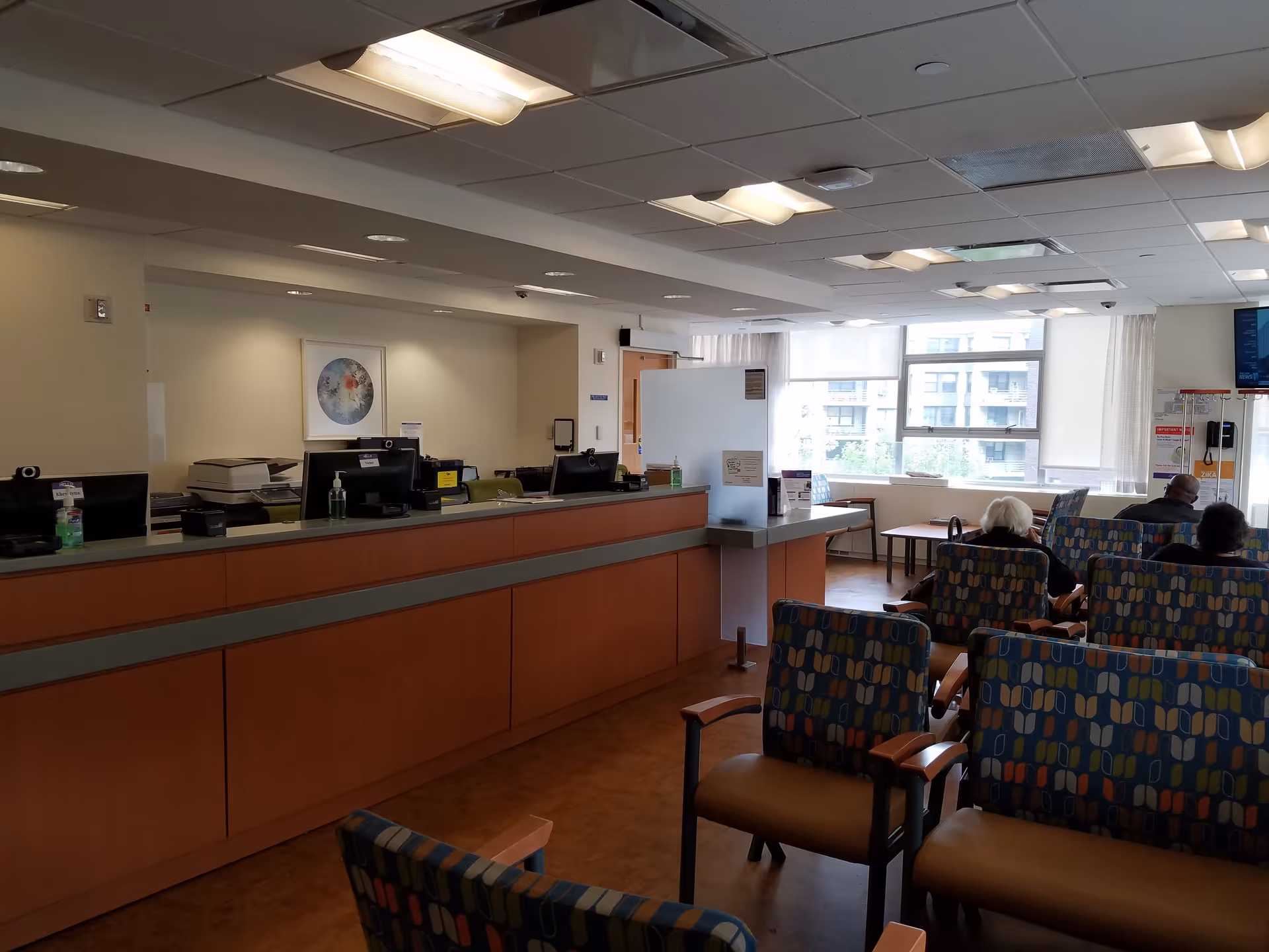 Interior reception desk and waiting area with chairs, computers, and large windows.