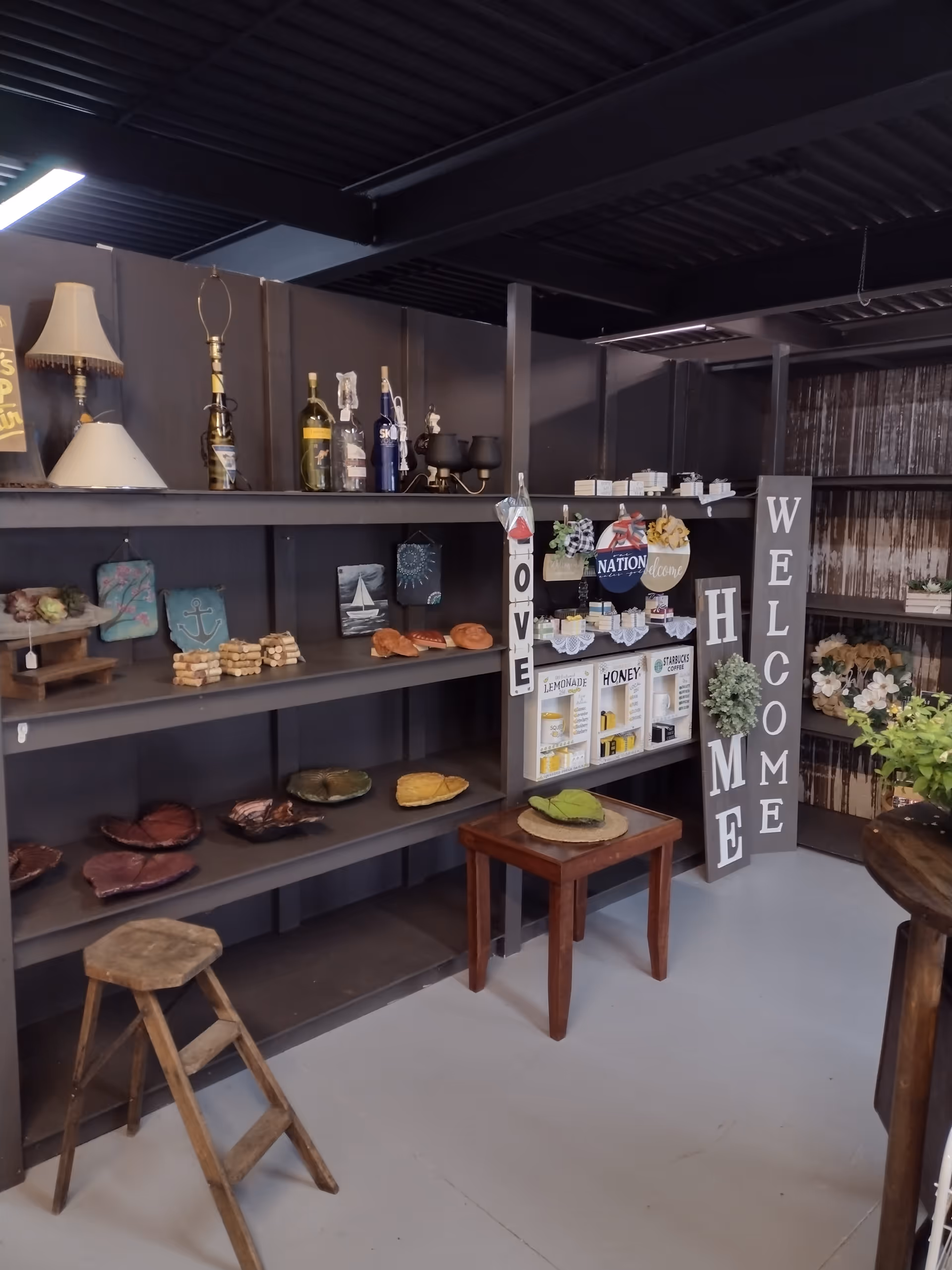 Interior display area with dark shelves, bottles, signs, and a Welcome column.