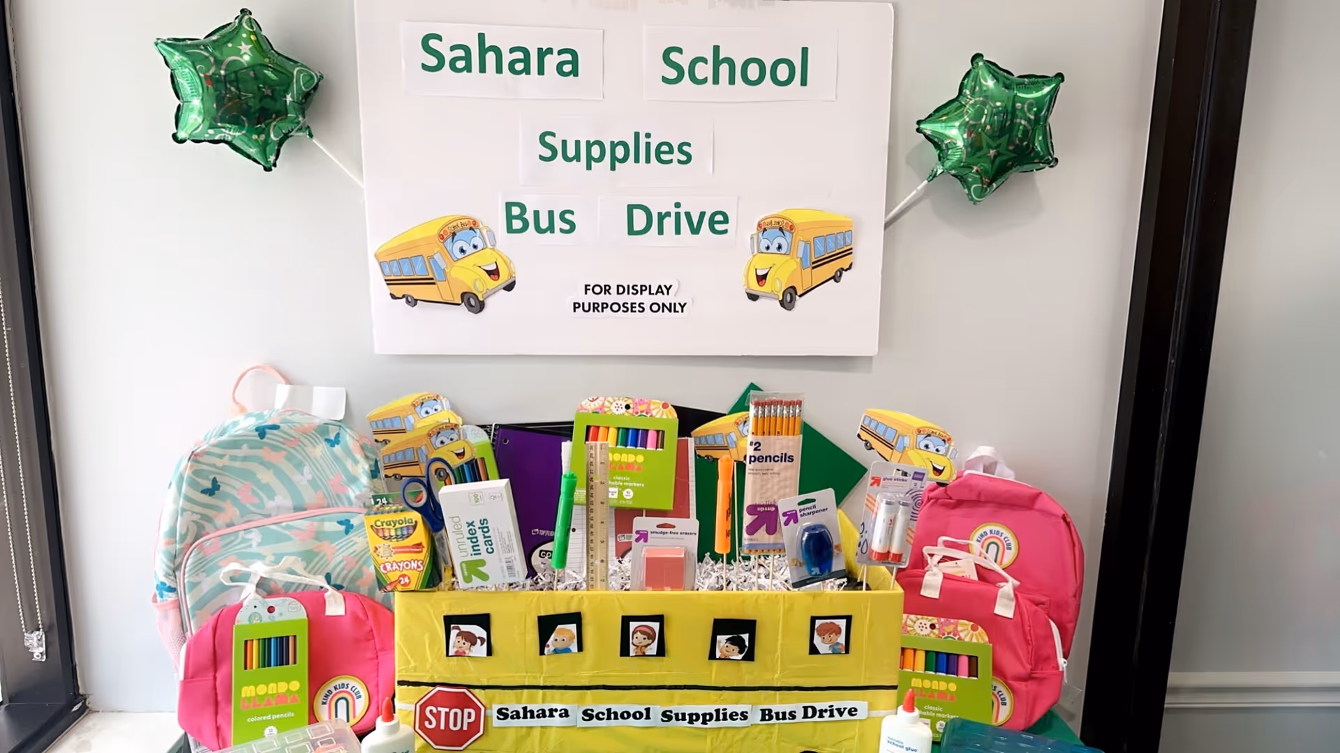Indoor display of Sahara School Supplies Bus Drive with backpacks and school supplies.