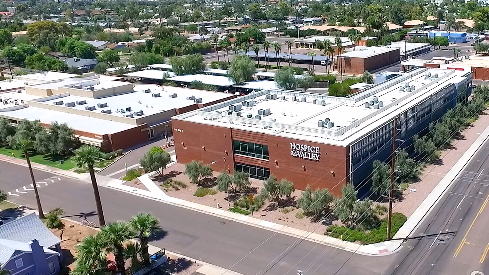 Aerial view of a large brick healthcare facility labeled Hospice Valley, with surrounding roads and trees.