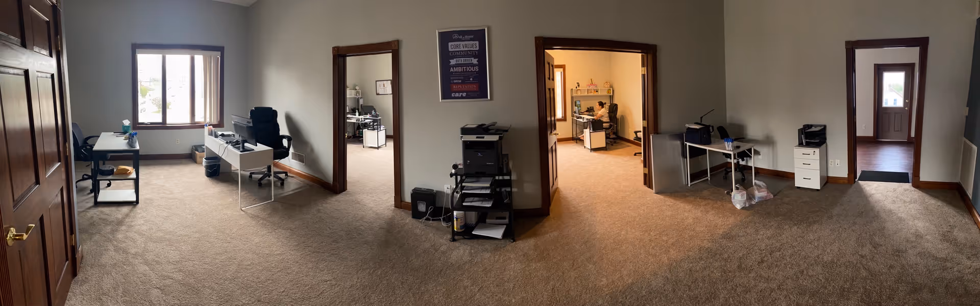 Panoramic interior of a senior facility office area with desks, chairs, and doorways.