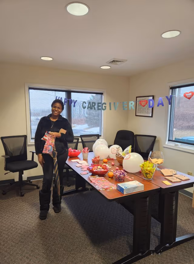 A person stands beside a decorated conference table with balloons indoors.