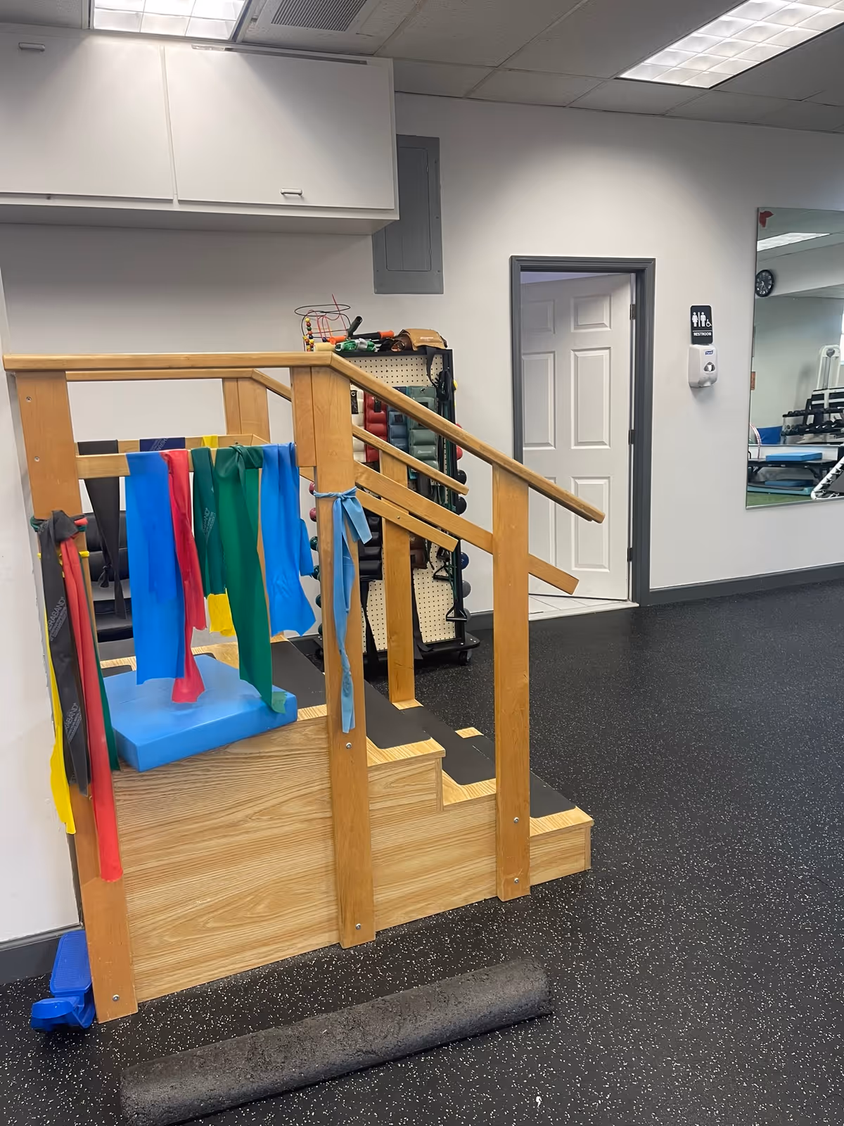 Wooden therapy platform with resistance bands and gym equipment in an interior exercise area