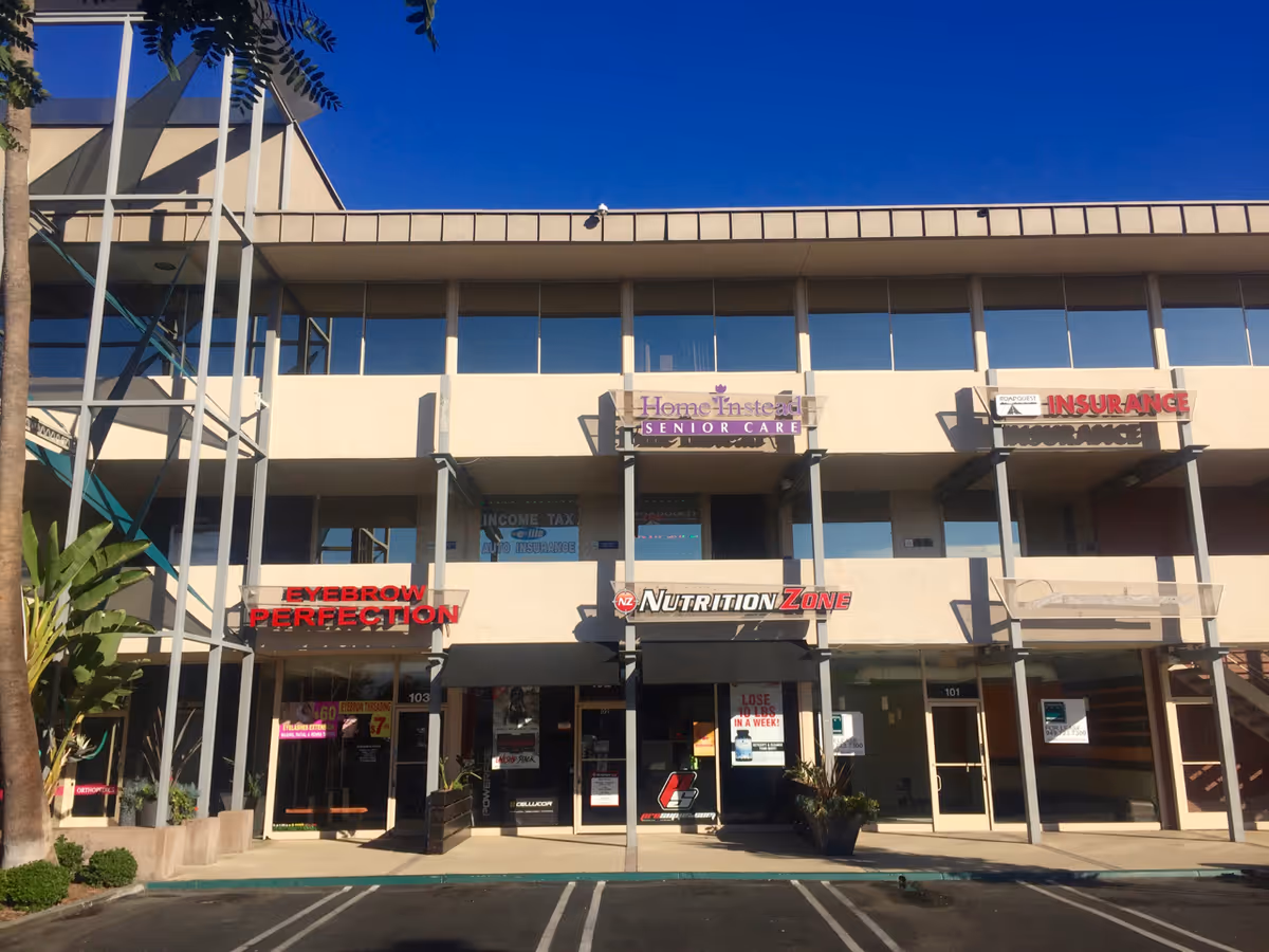 Two-story commercial building with glass storefronts and signs, including Home Instead Senior Care.