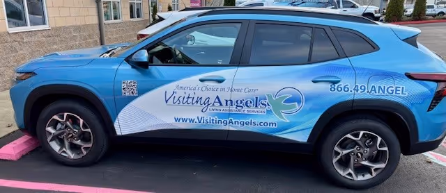 Blue Visiting Angels vehicle parked outside a facility with branding along its side.