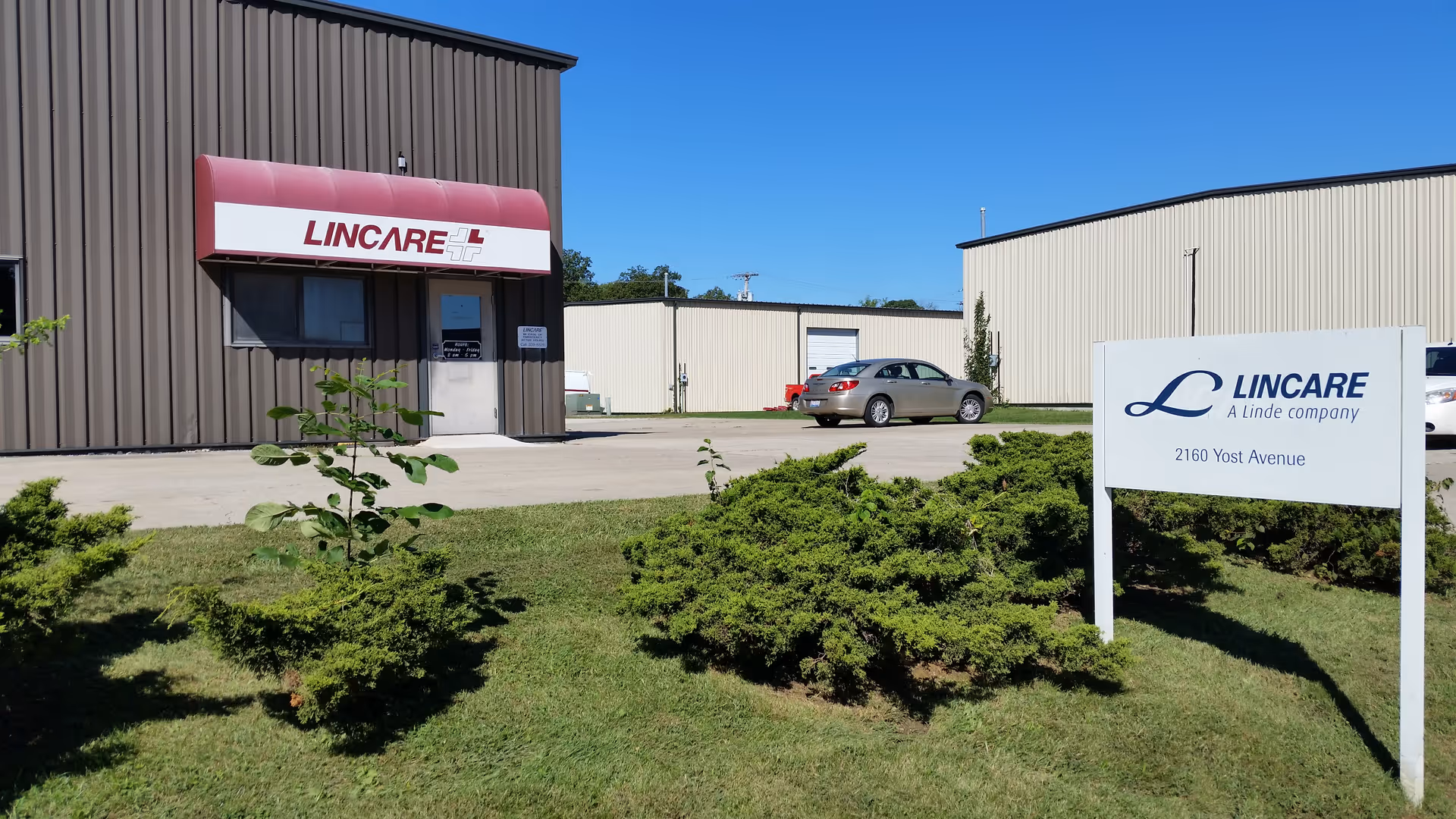 Exterior view of a Lincare facility entrance with a parking lot and landscaped shrubbery.