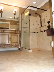 Elegant bathroom with glass shower enclosure, tiled walls, and ornate wooden vanity.