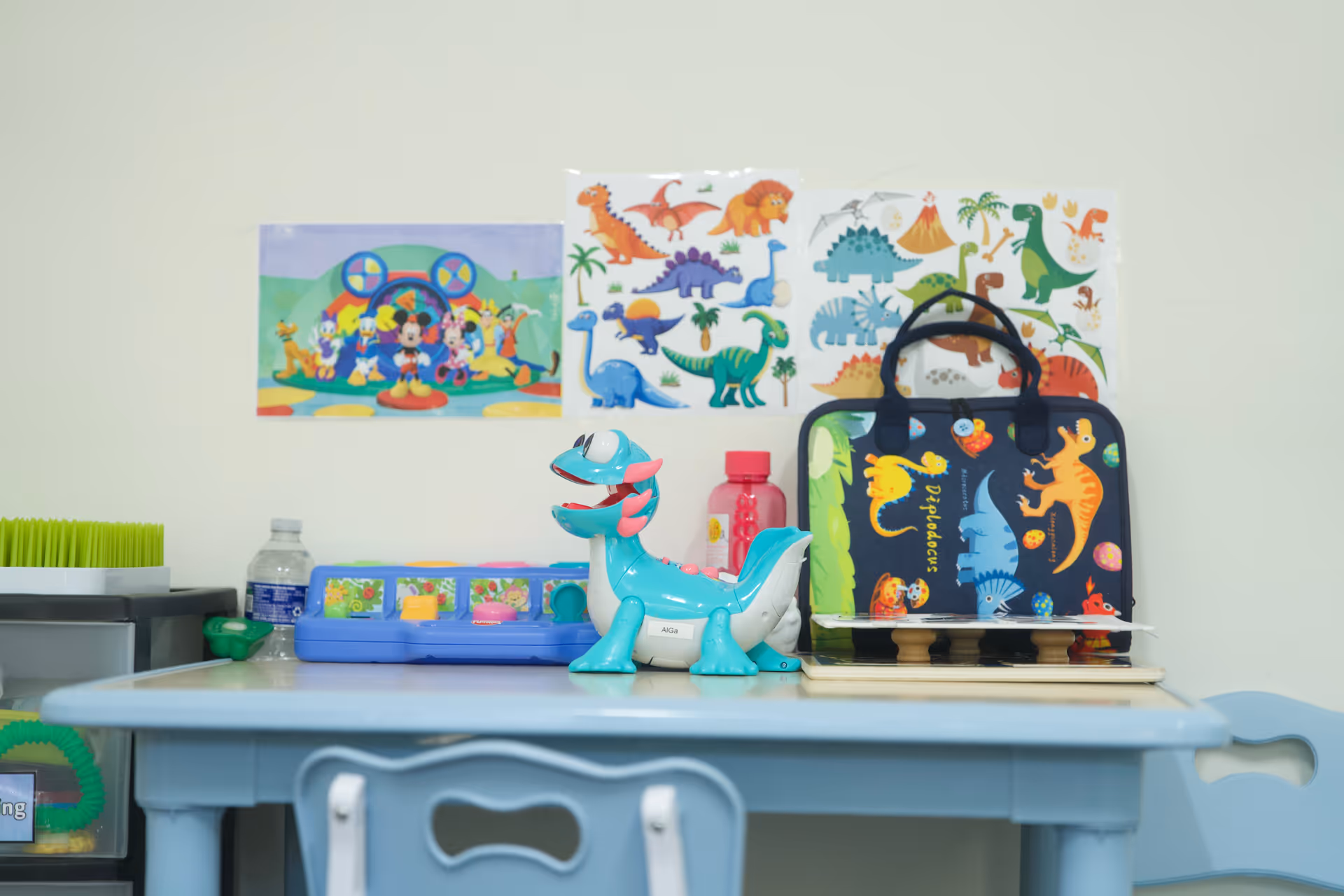 Child-friendly play area with dinosaur toys on a blue table and wall posters