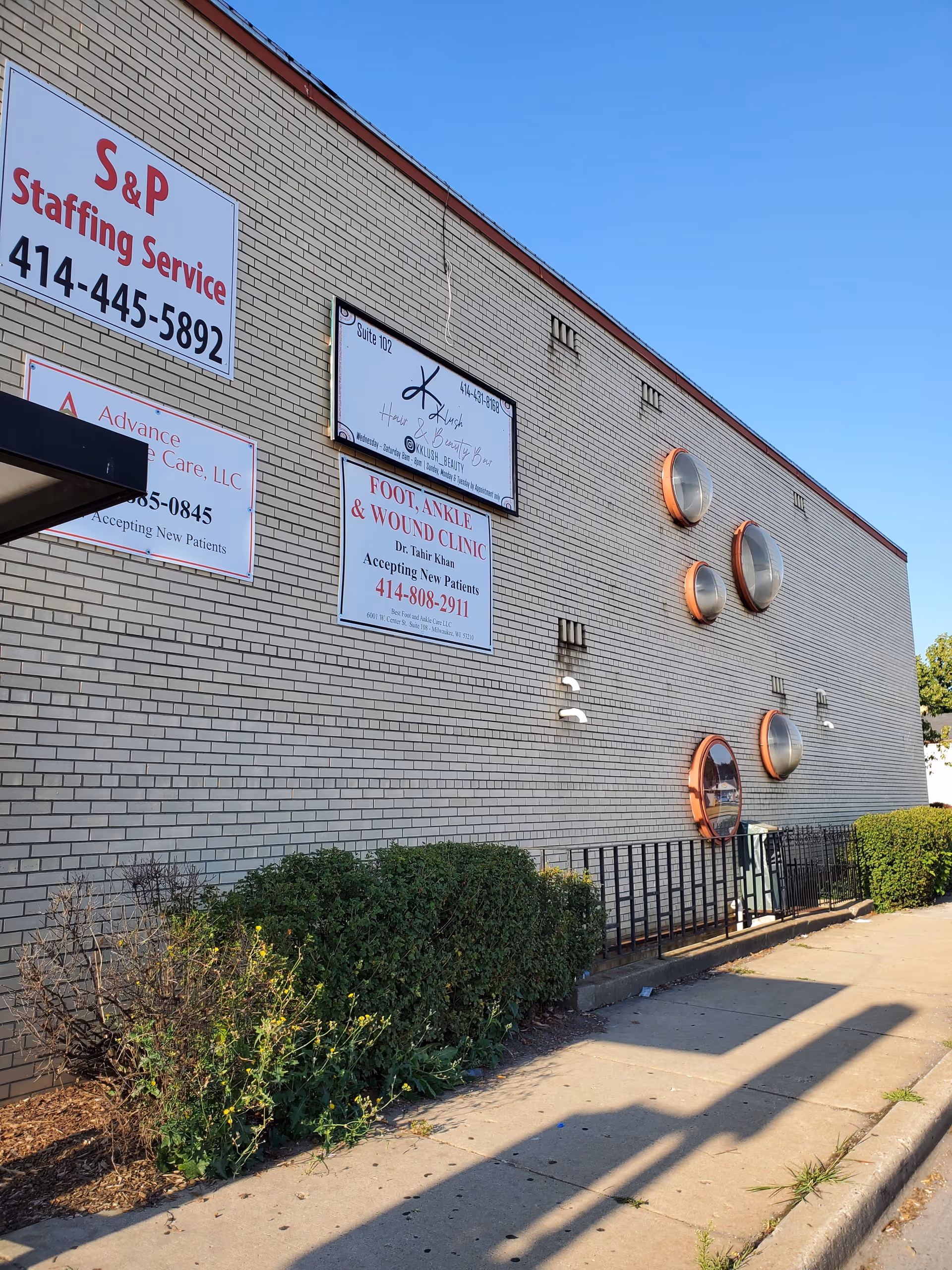 A brick exterior wall displays business signs including Advance Home Care LLC and a sidewalk.
